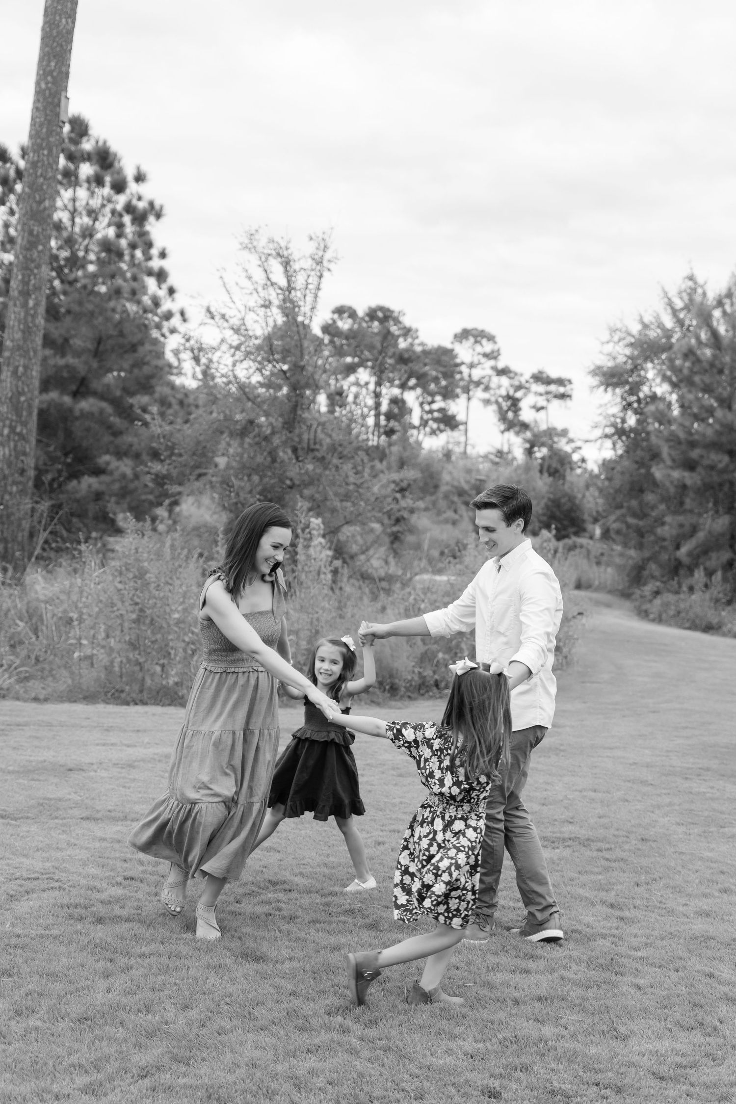 People dancing and twirling in a grassy field captured in black and white.