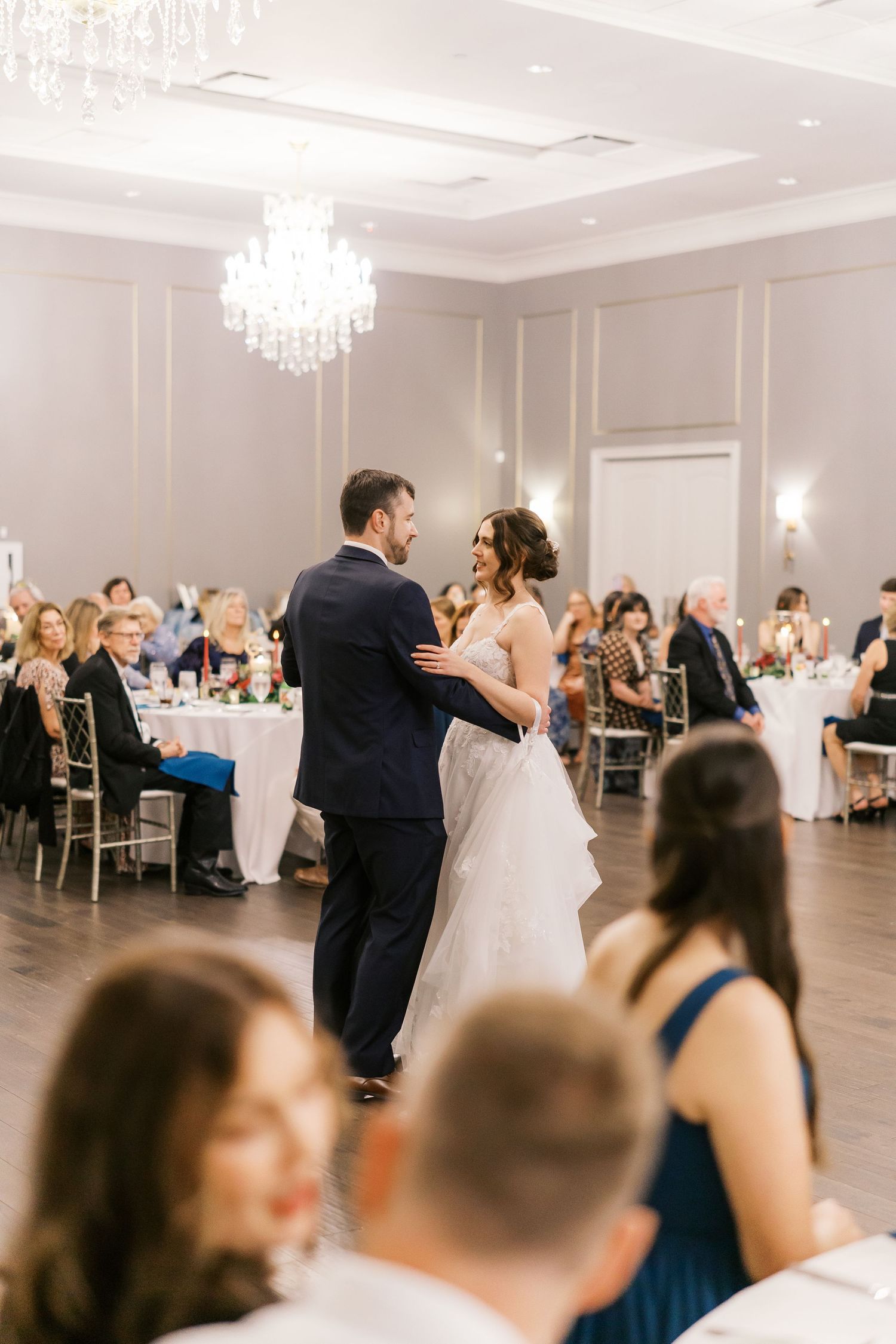 Wedding reception in an elegant ballroom with crystal chandeliers and formal table settings.