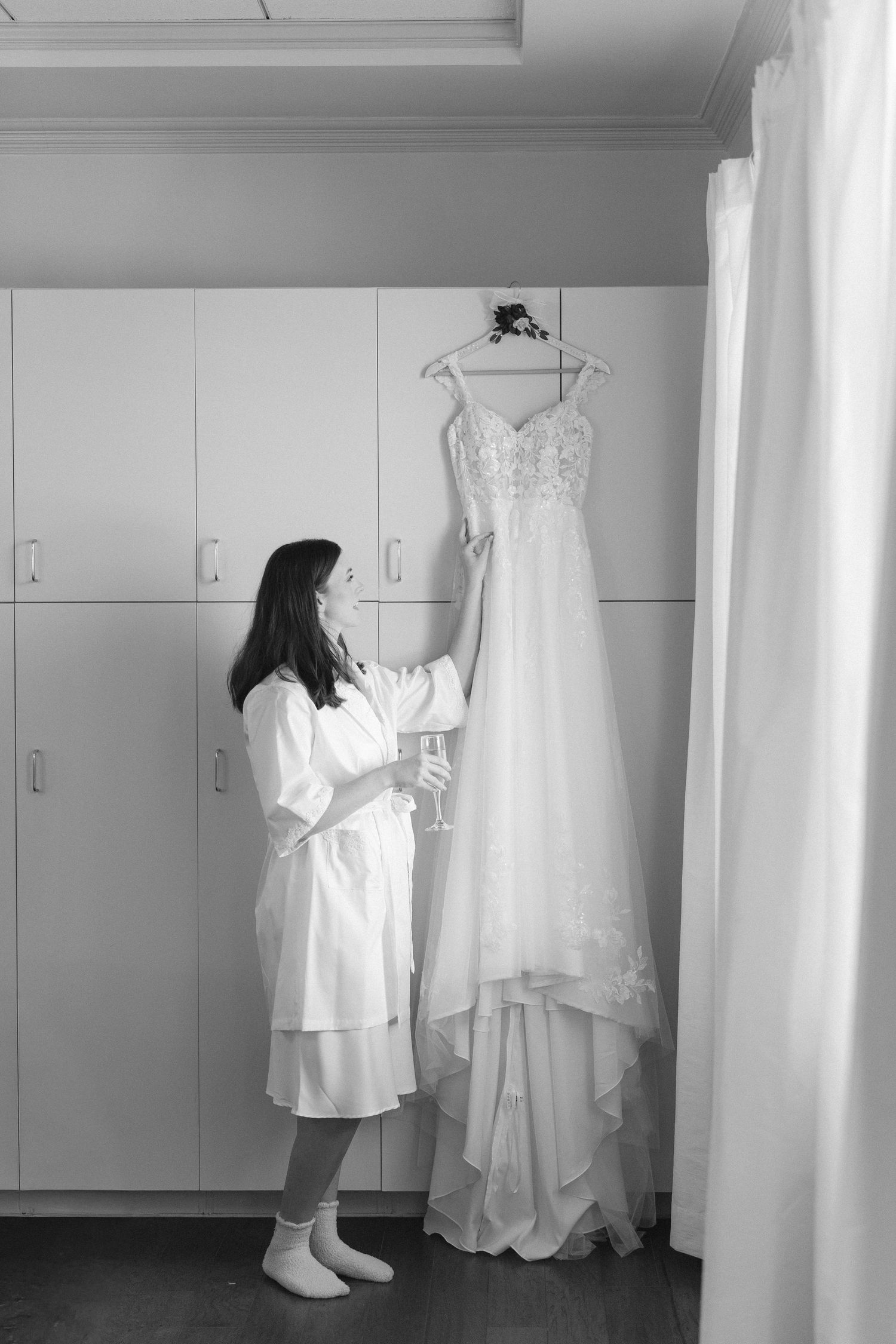 Wedding preparation room with white dresses and garments hanging against minimalist white closets.