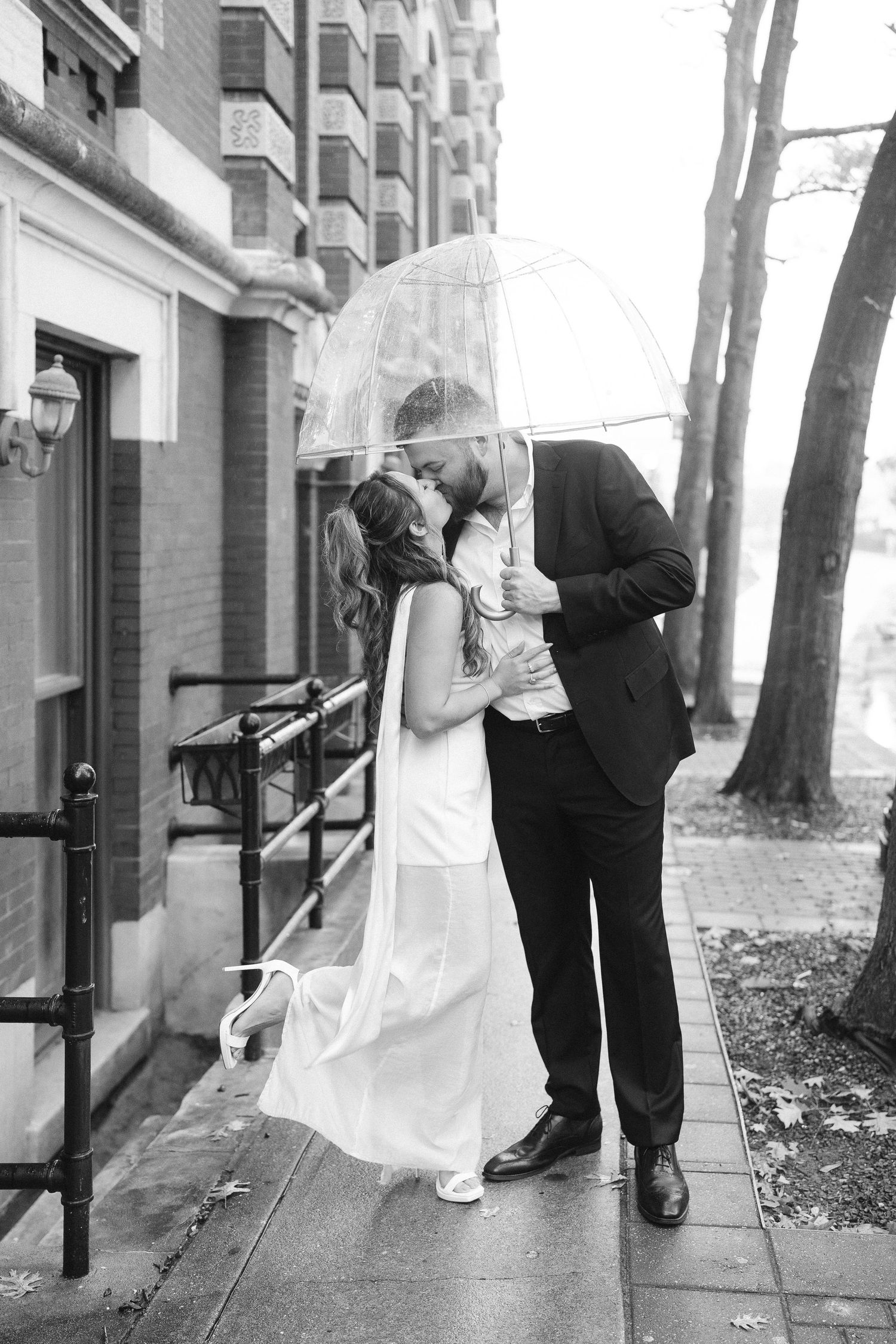 Black and white wedding photo series showing playful moments near a building entrance.