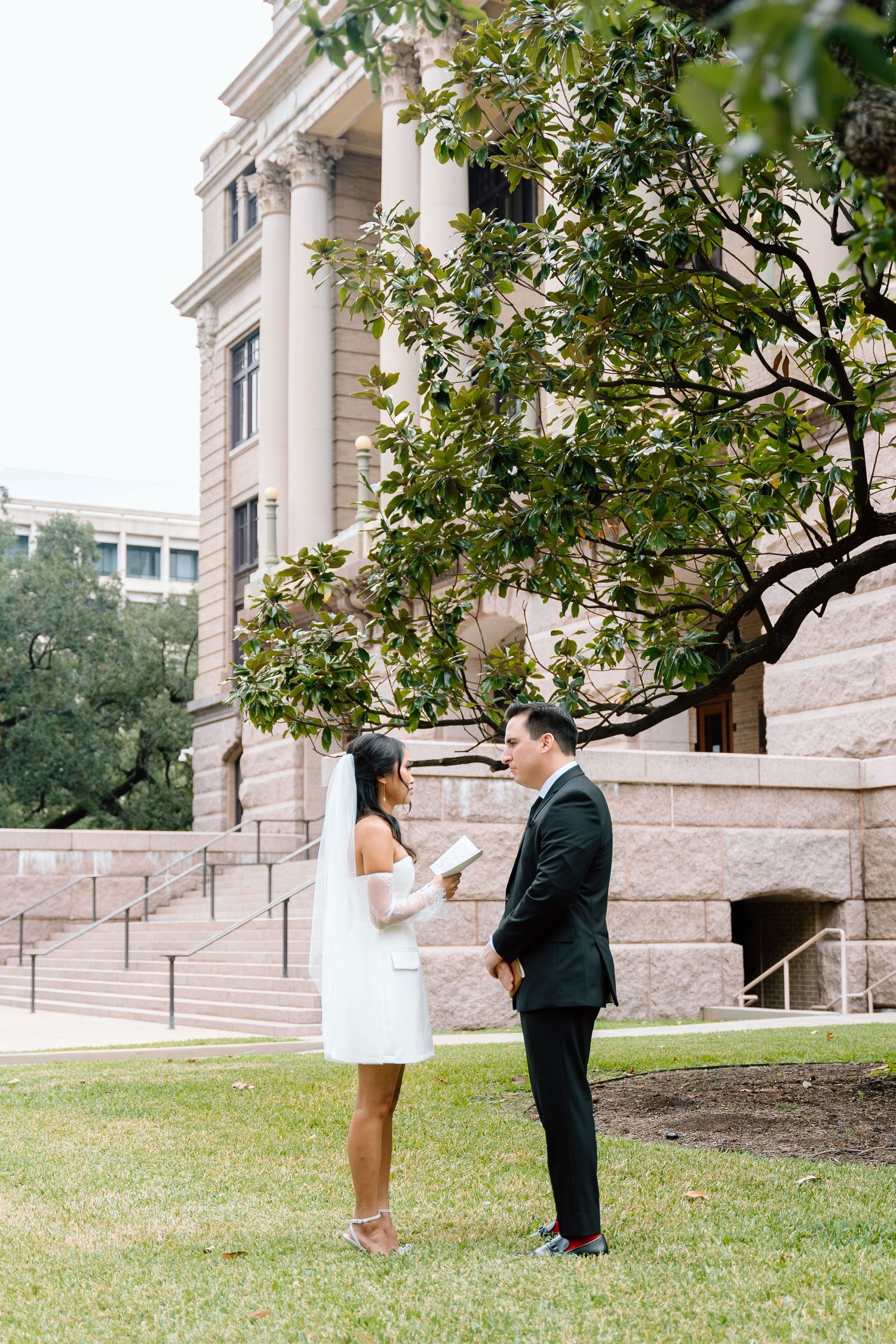 Wedding couple shares first look moments outside a grand stone building.