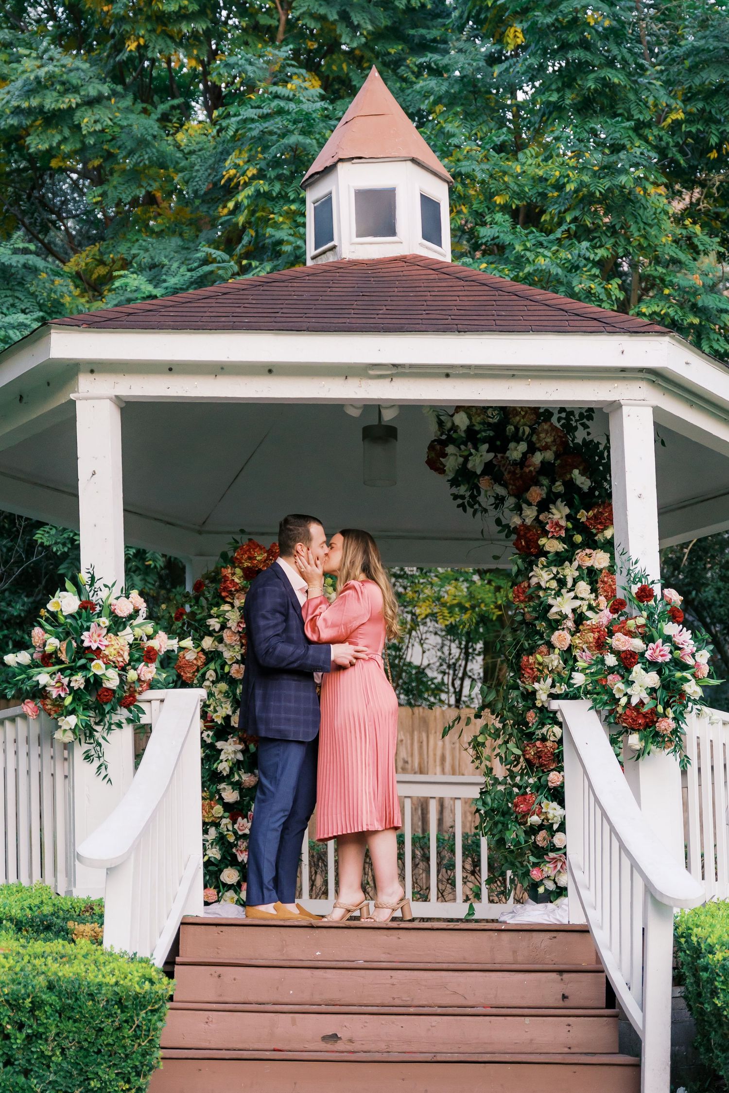 A tender moment captured between two people on a flower-decorated gazebo deck.