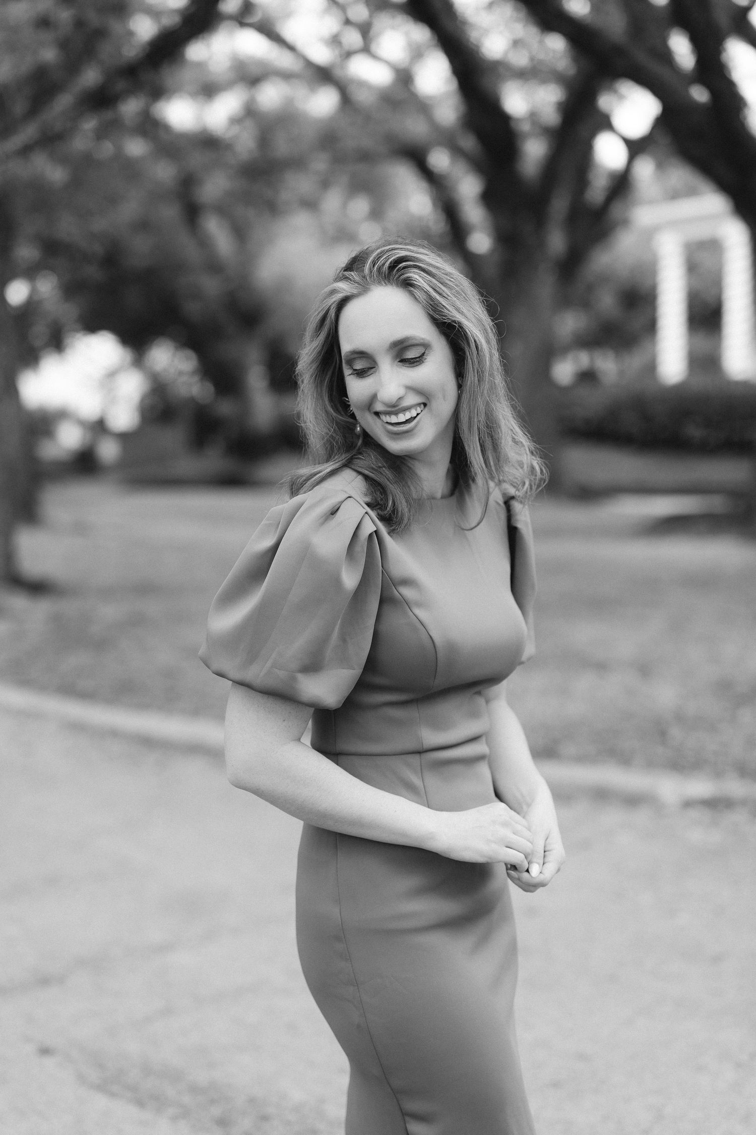 Black and white maternity photos showing joyful moments on a tree-lined path.