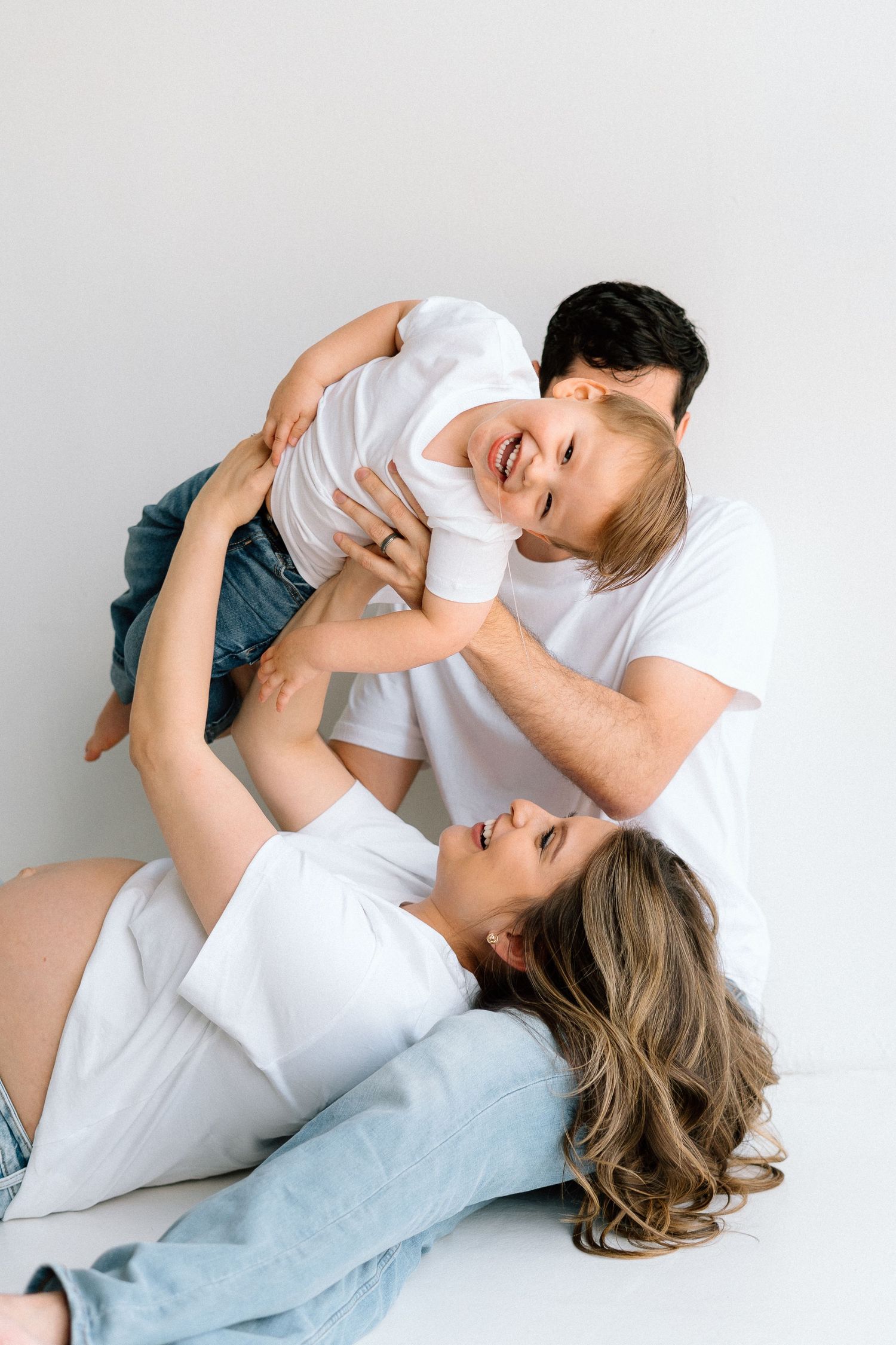 Intimate studio photoshoot featuring tender embraces against a white background.