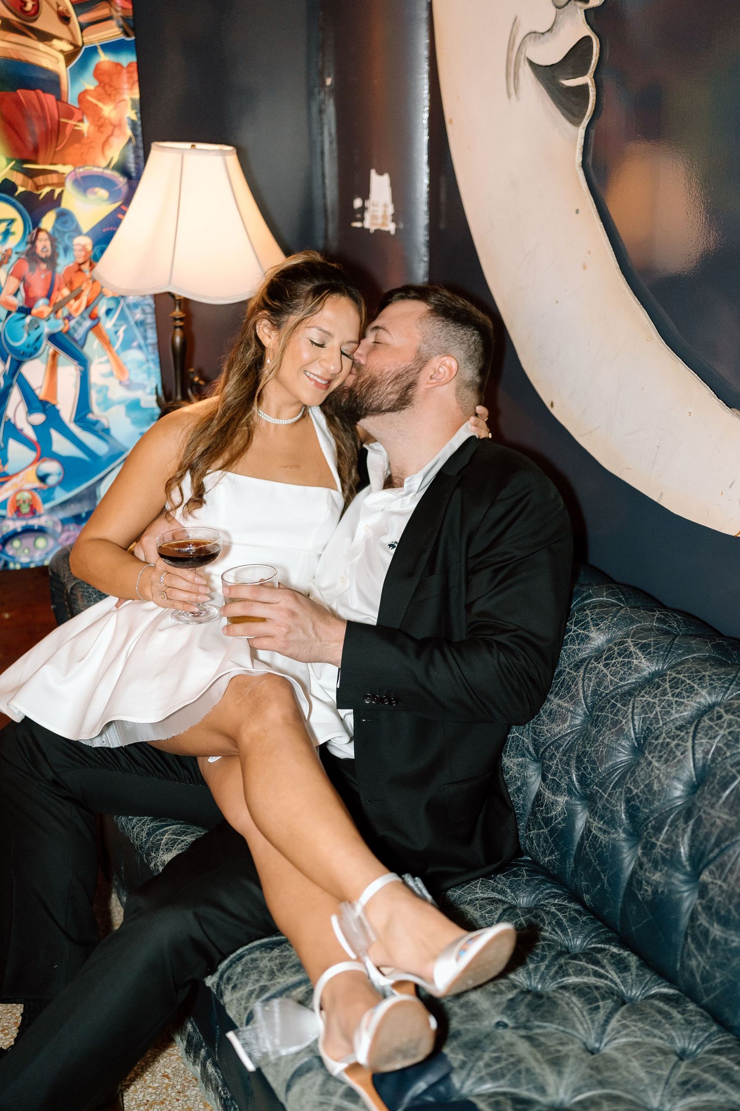 Couple in formal attire shares intimate moment on vintage patterned couch.