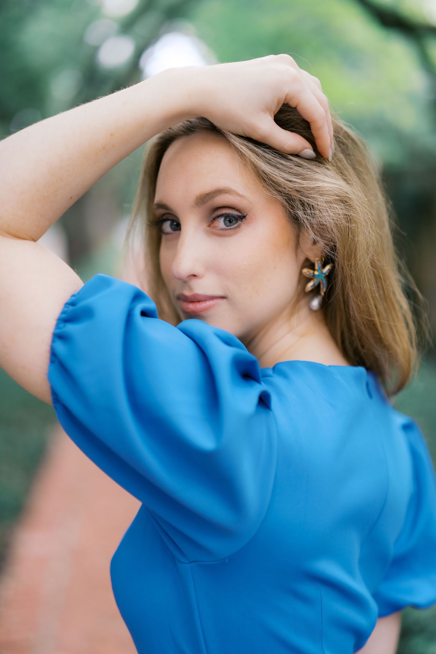 Portrait series showing someone in a vibrant blue top against a soft natural background.
