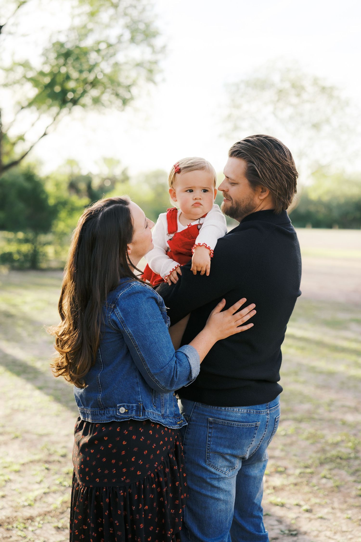 A family sharing affectionate moments together in an outdoor setting at sunset.