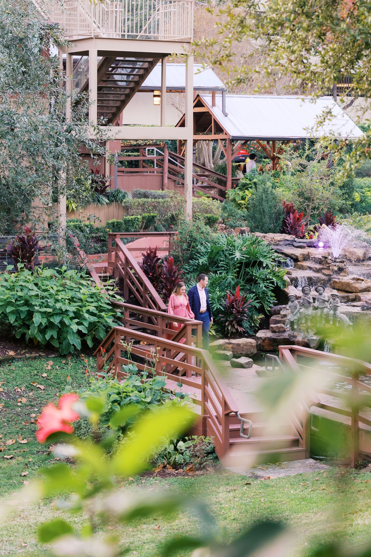 Garden walkway with wooden steps and railings surrounded by lush vegetation.