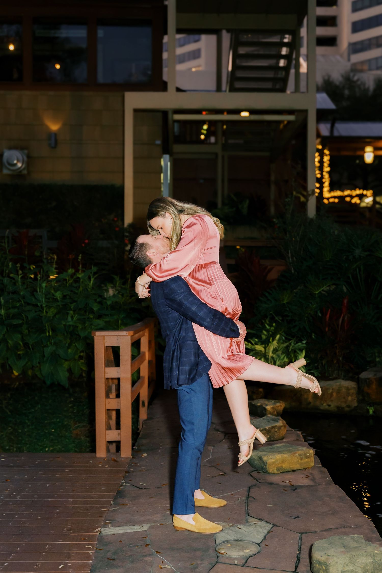 Playful engagement photos showing a couple embracing by garden steps at twilight.