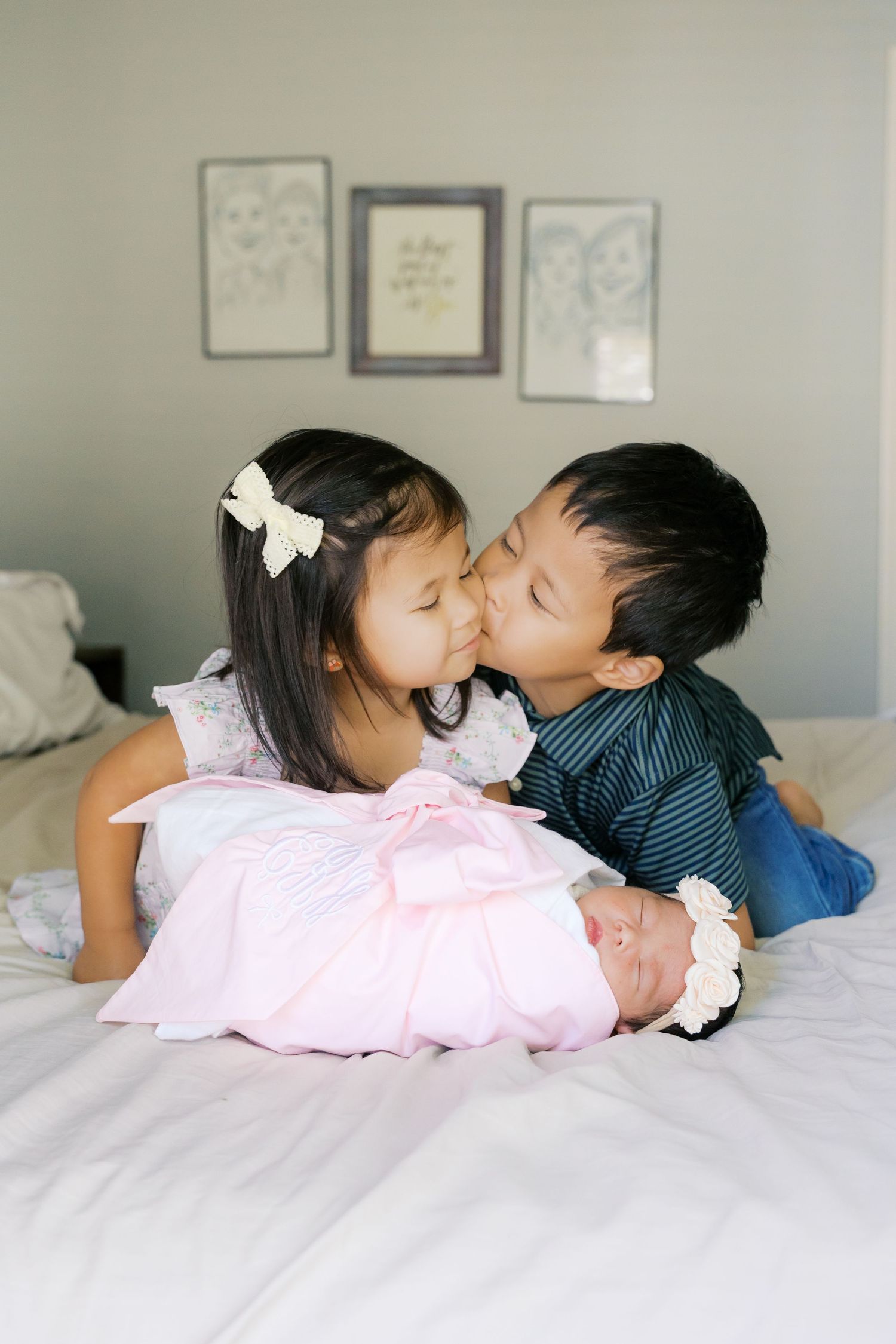 Siblings sharing sweet moments together on white bedding during a photo session.