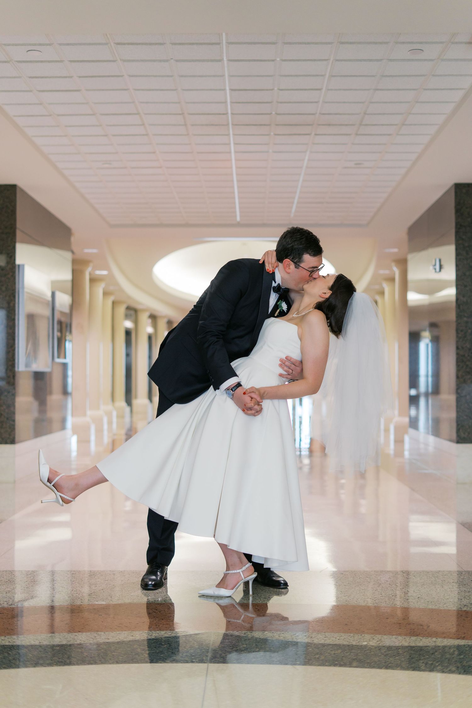 Romantic wedding poses captured in a modern building hallway.