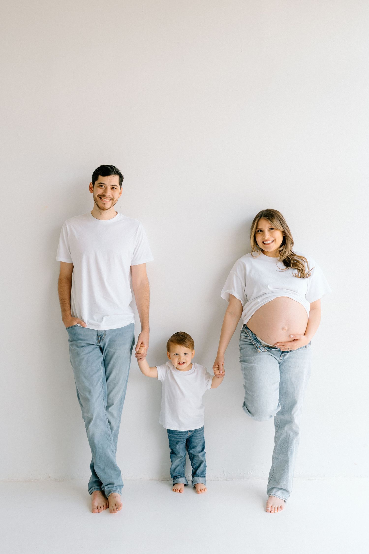 Modern minimalist family portrait series with matching outfits showing pregnancy progression.