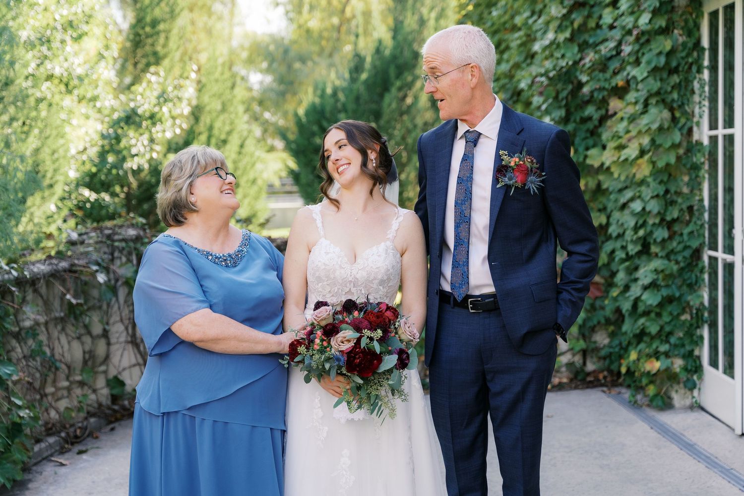 Wedding party shares emotional moments in garden setting with ivy-covered walls.