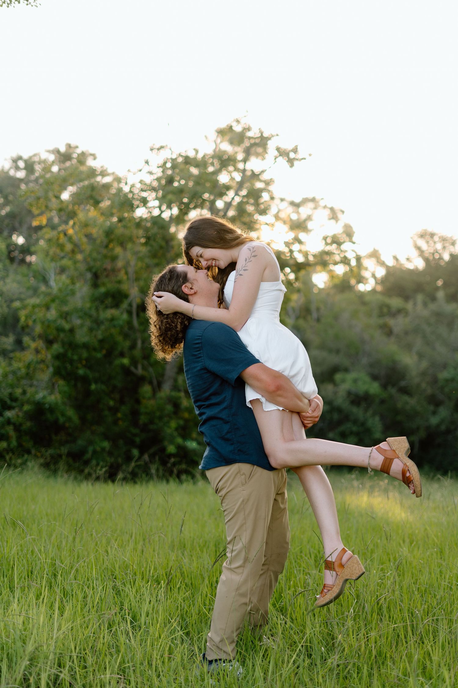 Playful spinning and lifting poses in a sunlit meadow during golden hour.