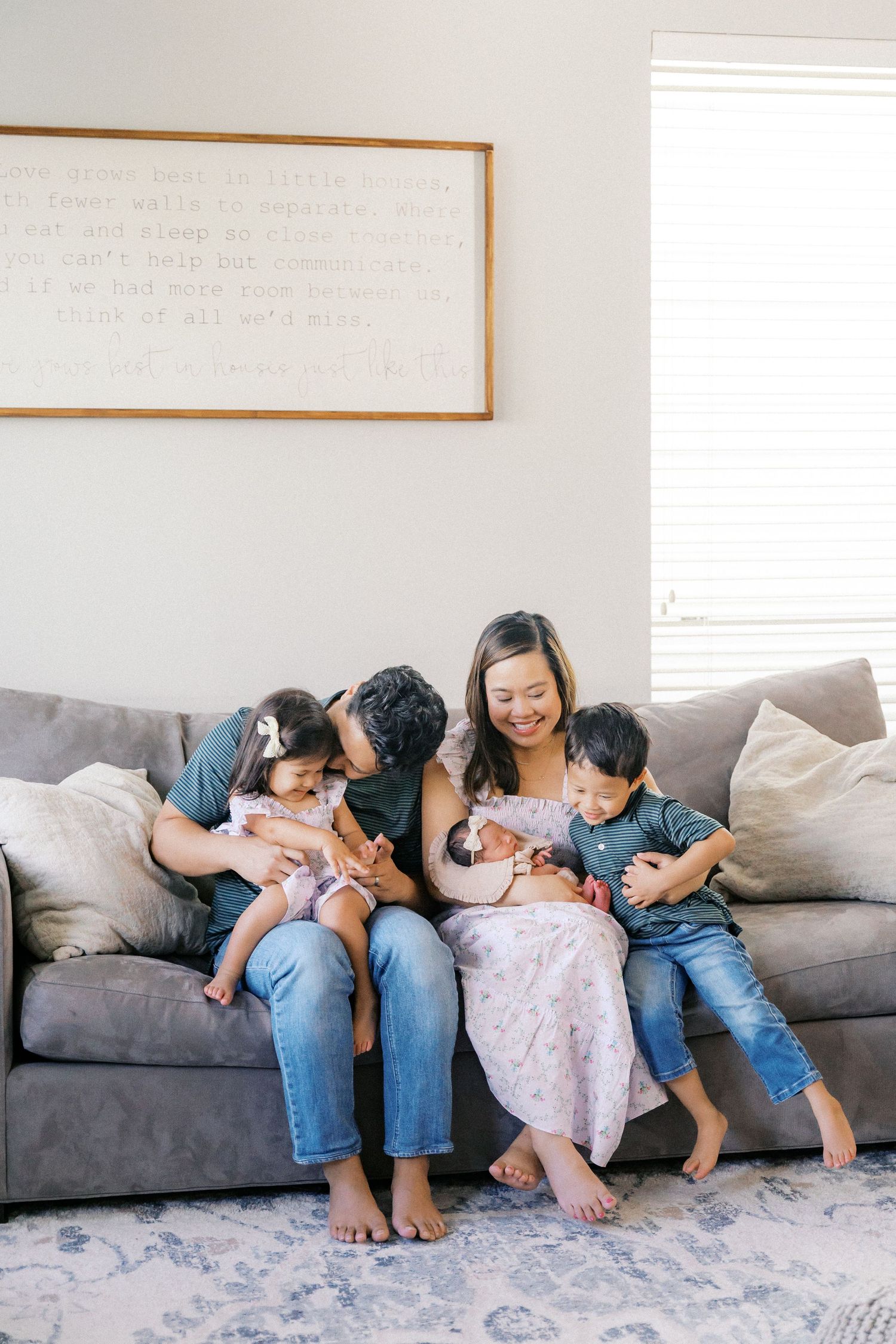 Family shares playful moment while lounging on gray sofa.