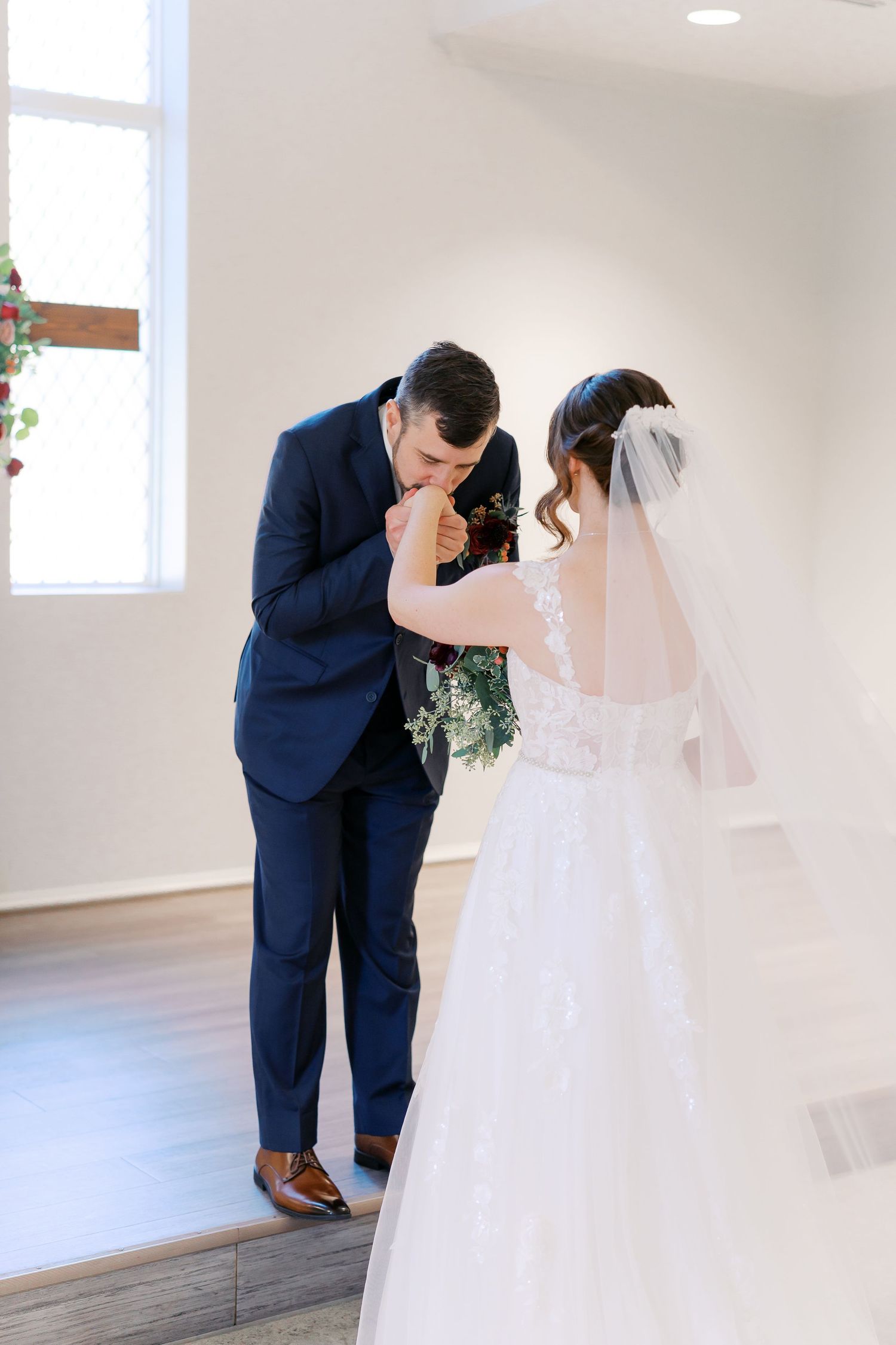 First look wedding moment captured in an intimate white room with natural lighting.