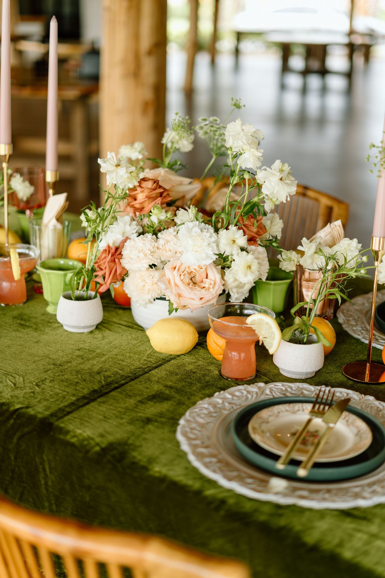 Elegant wedding table setting with green velvet tablecloth and colorful floral centerpieces.