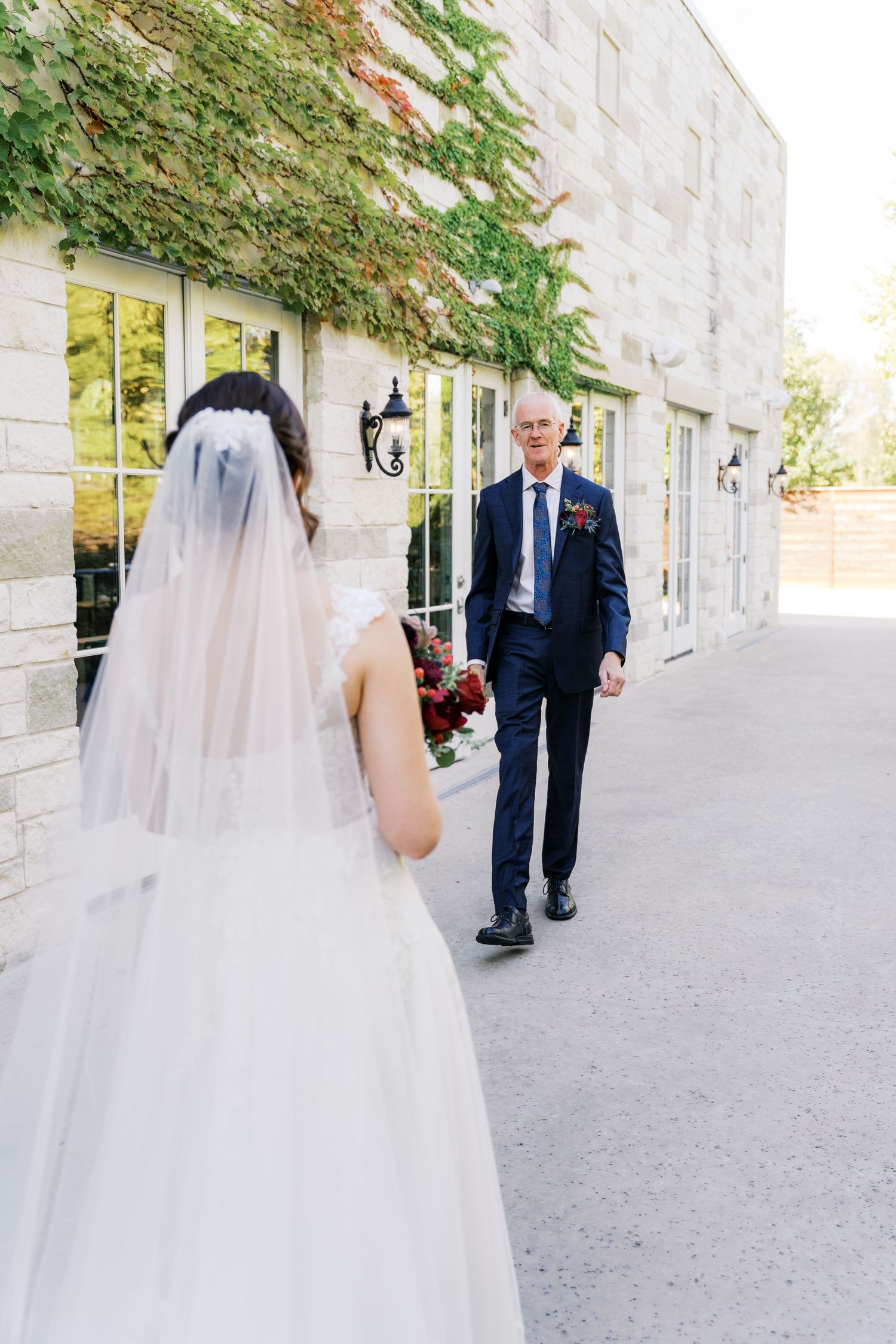 First look moment between couple outside ivy-covered stone building.