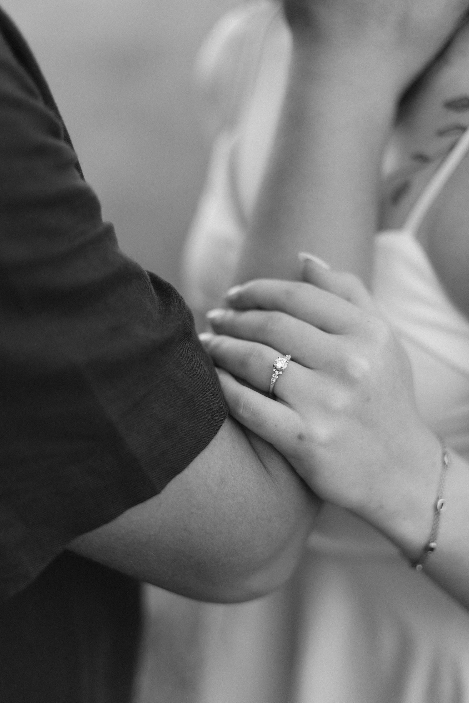 Close-up shot of hands with engagement ring against blurred background.
