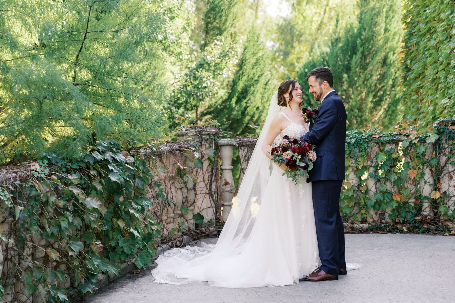 Wedding couple sharing tender moments in an outdoor garden setting with ivy walls.