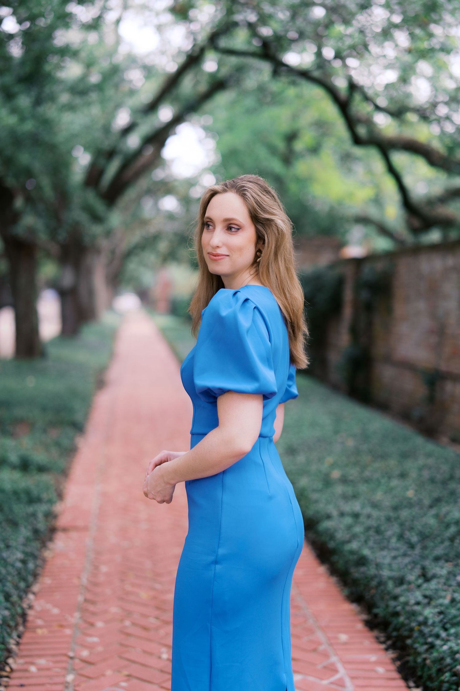A tree-lined brick pathway creates a beautiful backdrop for a maternity photoshoot.