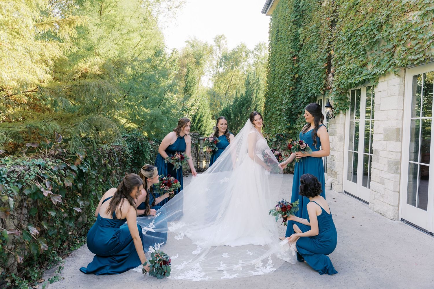 Wedding party in navy blue dresses and white gown posing outside venue.