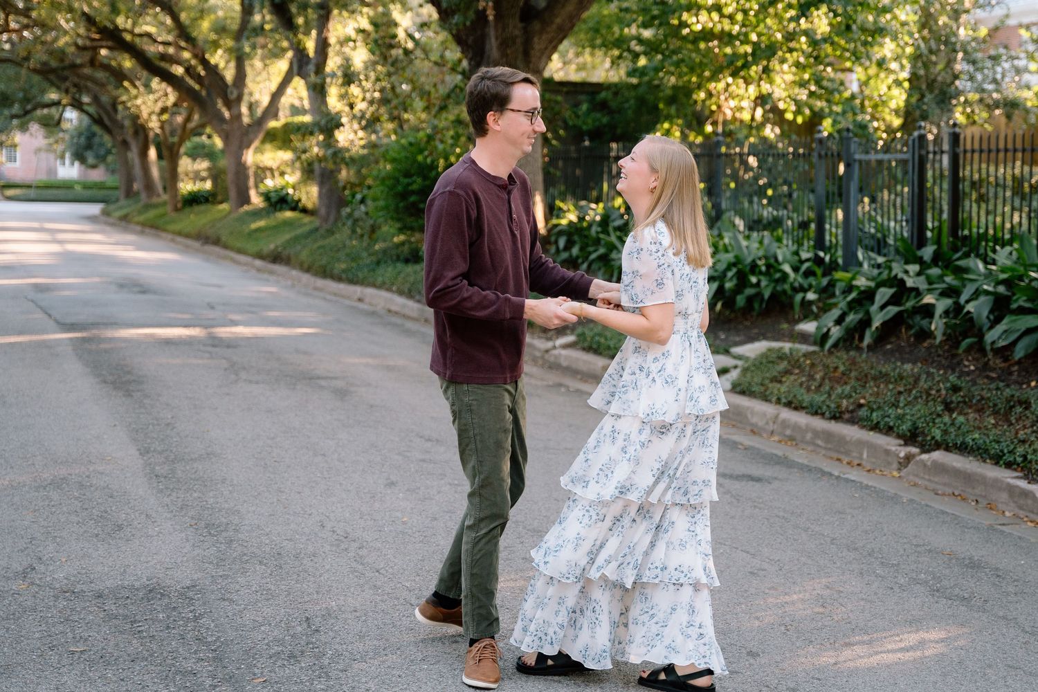 A couple walks hand in hand down a sunlit garden path.