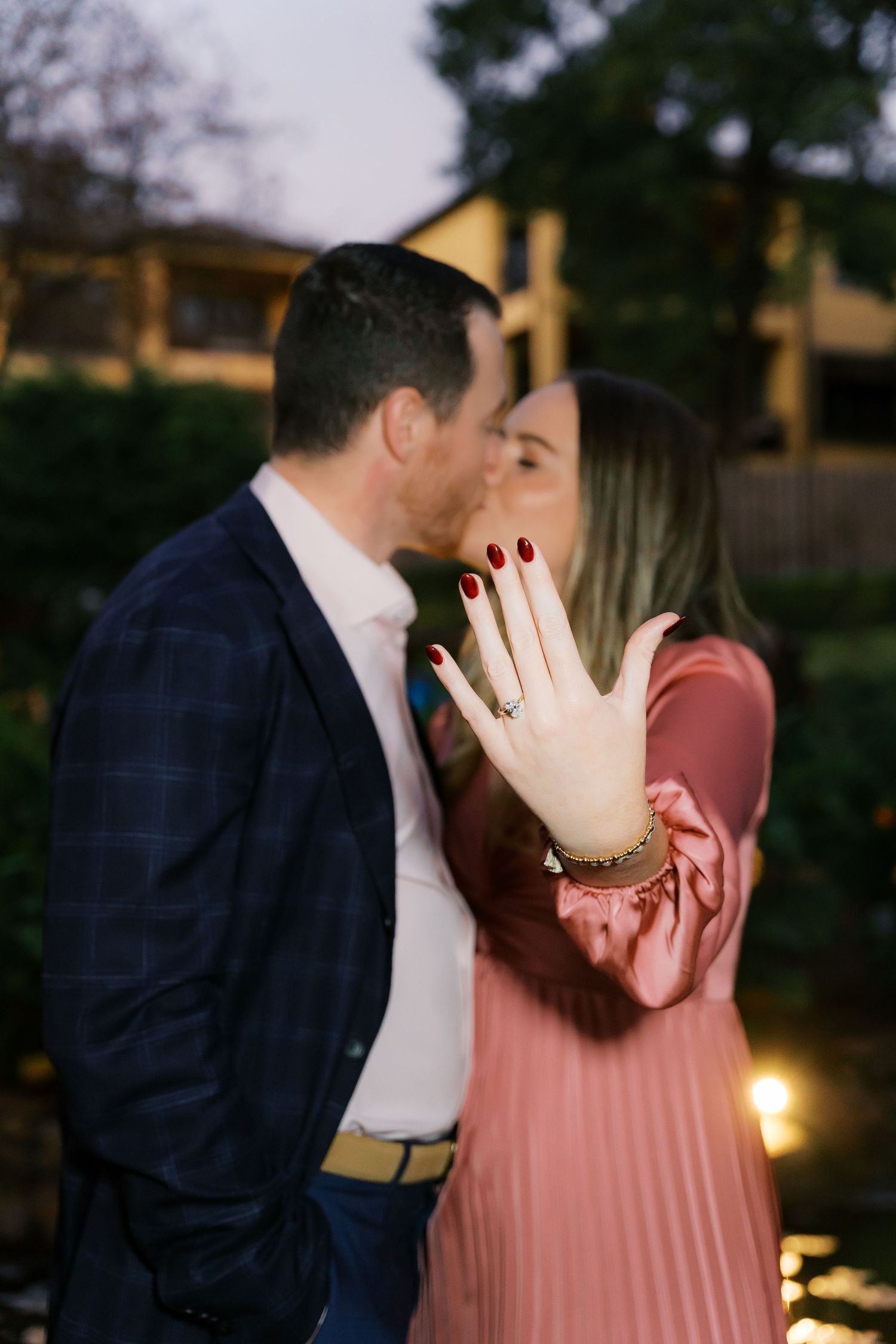 Romantic proposal moment captured in a series of photos by a lit garden at dusk.