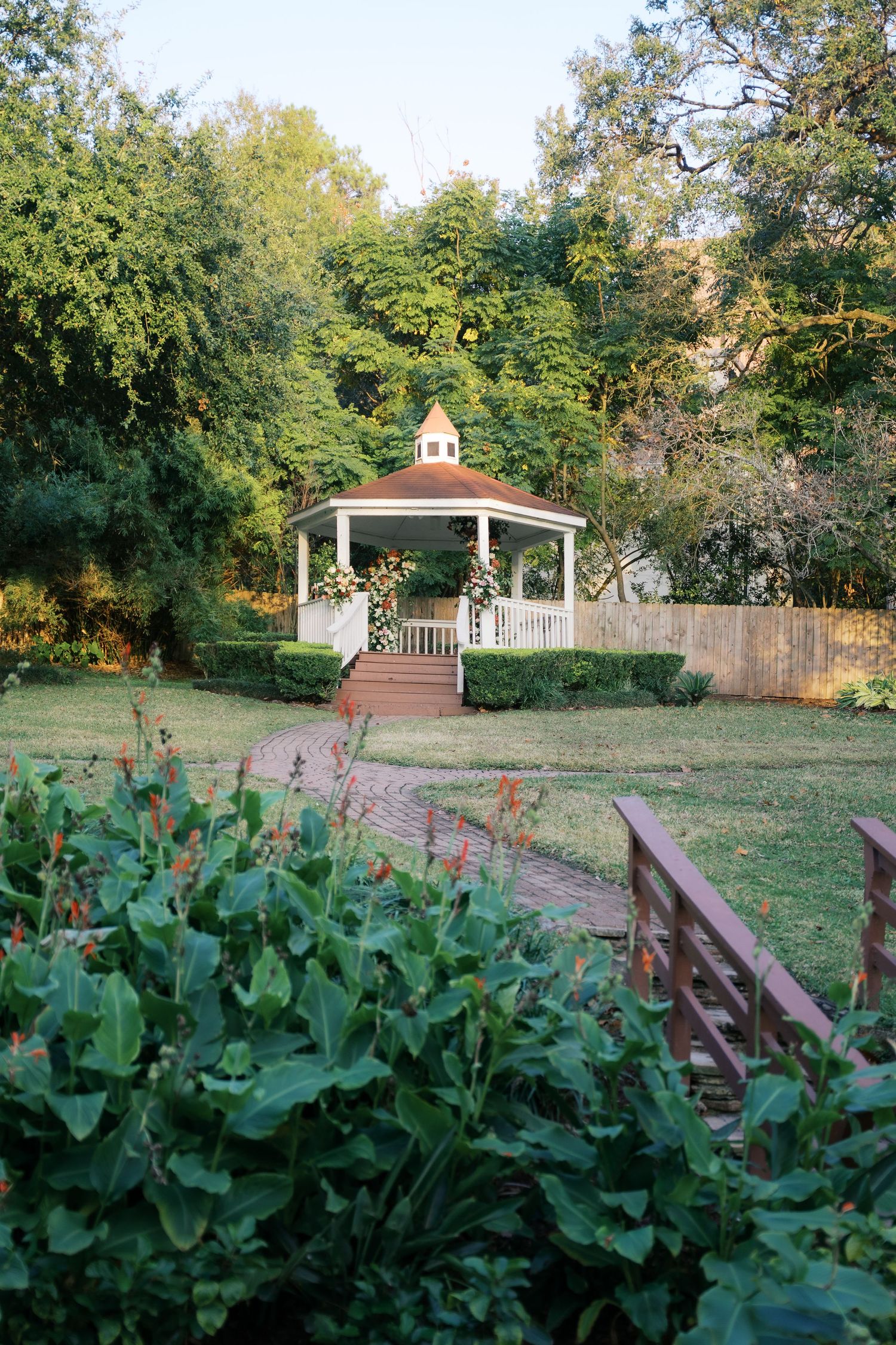 A scenic garden path leads to a white gazebo surrounded by lush greenery.