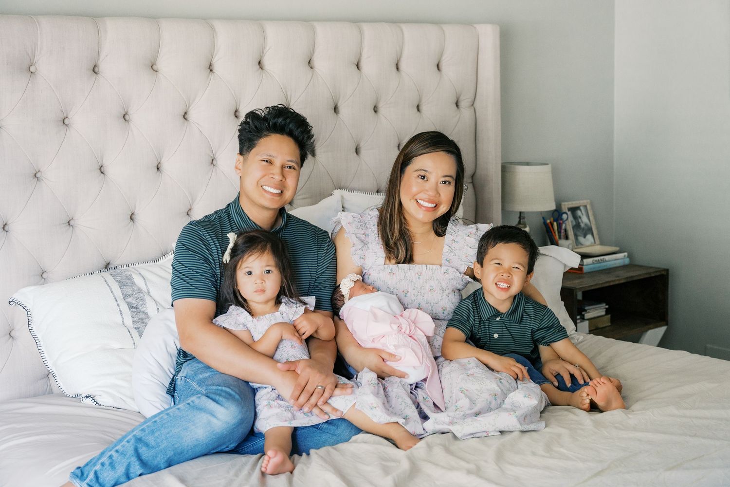 A family relaxing together on a tufted headboard bed during an indoor photoshoot.