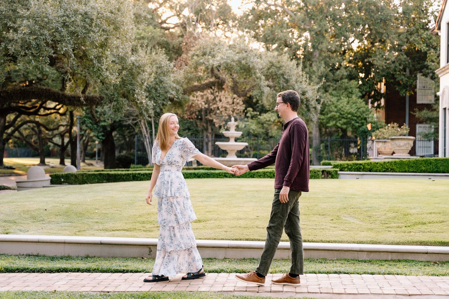 Couple strolls through a park garden setting during a romantic photo session.