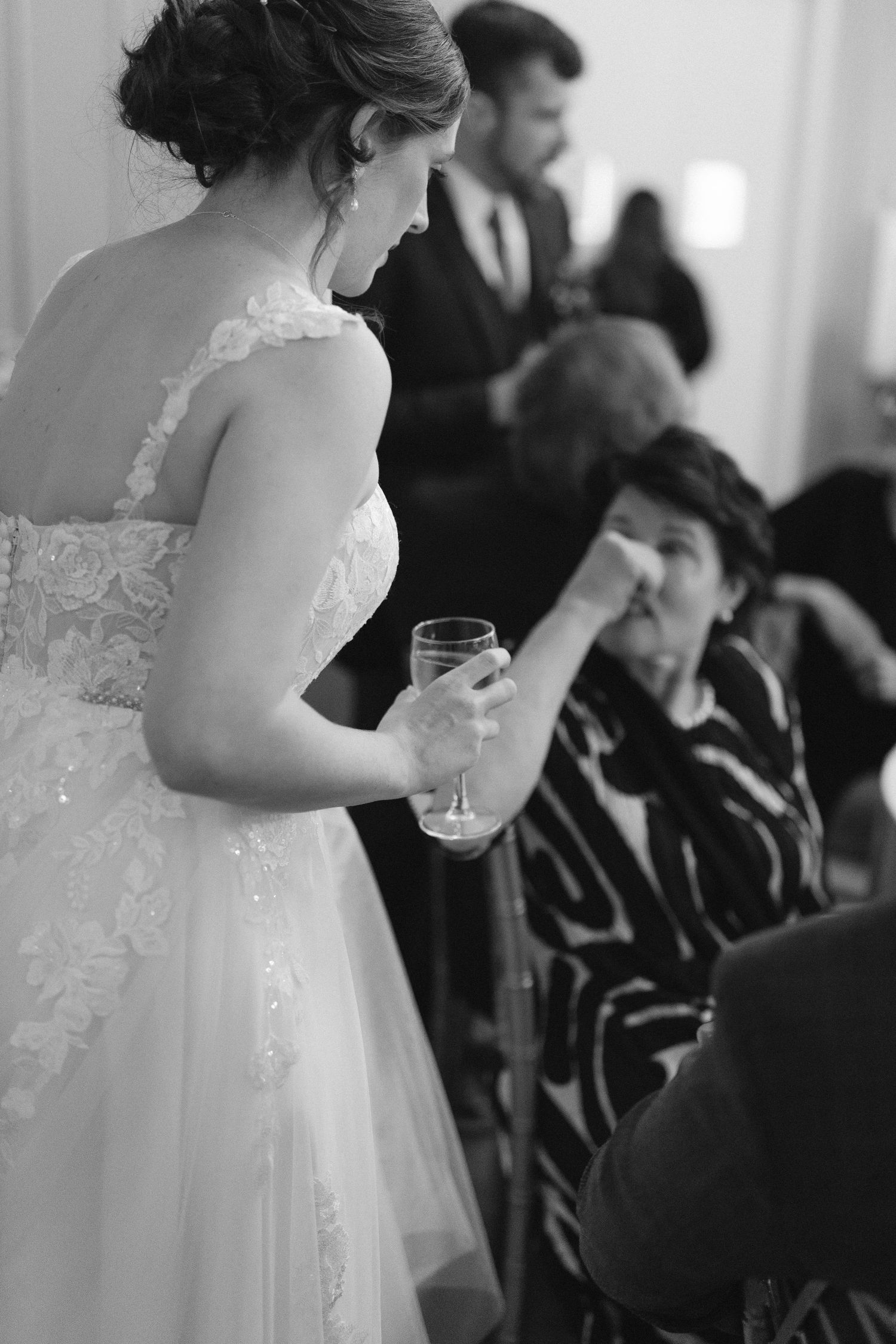 Wedding guests in formal attire seated in rows during an indoor ceremony.
