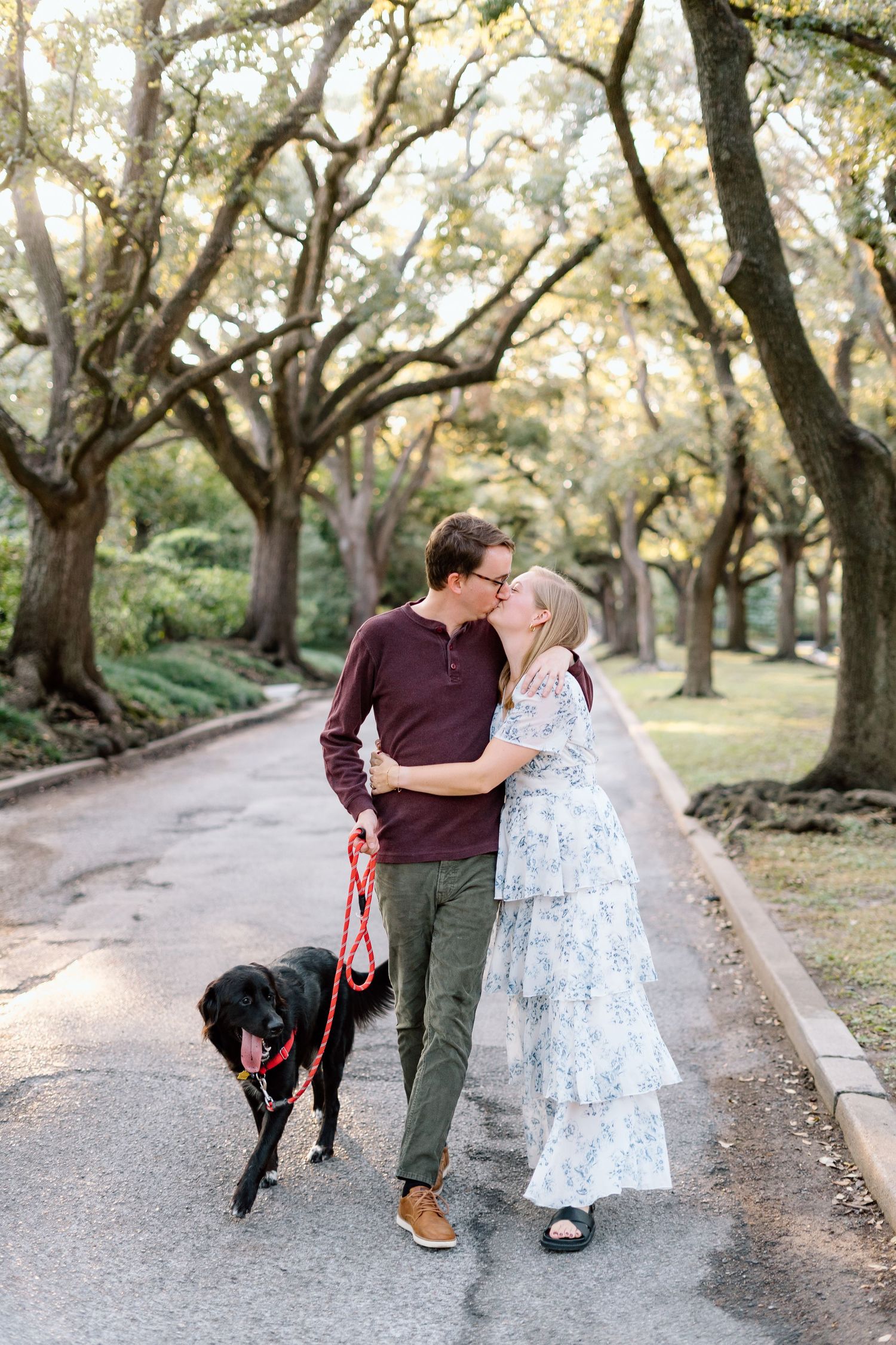 A couple shares intimate moments on a tree-lined path at sunset.