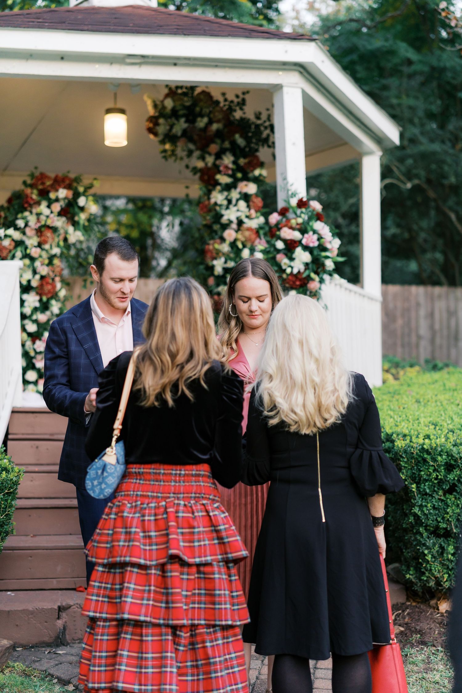 People gather on gazebo steps with one wearing a distinctive red plaid skirt.