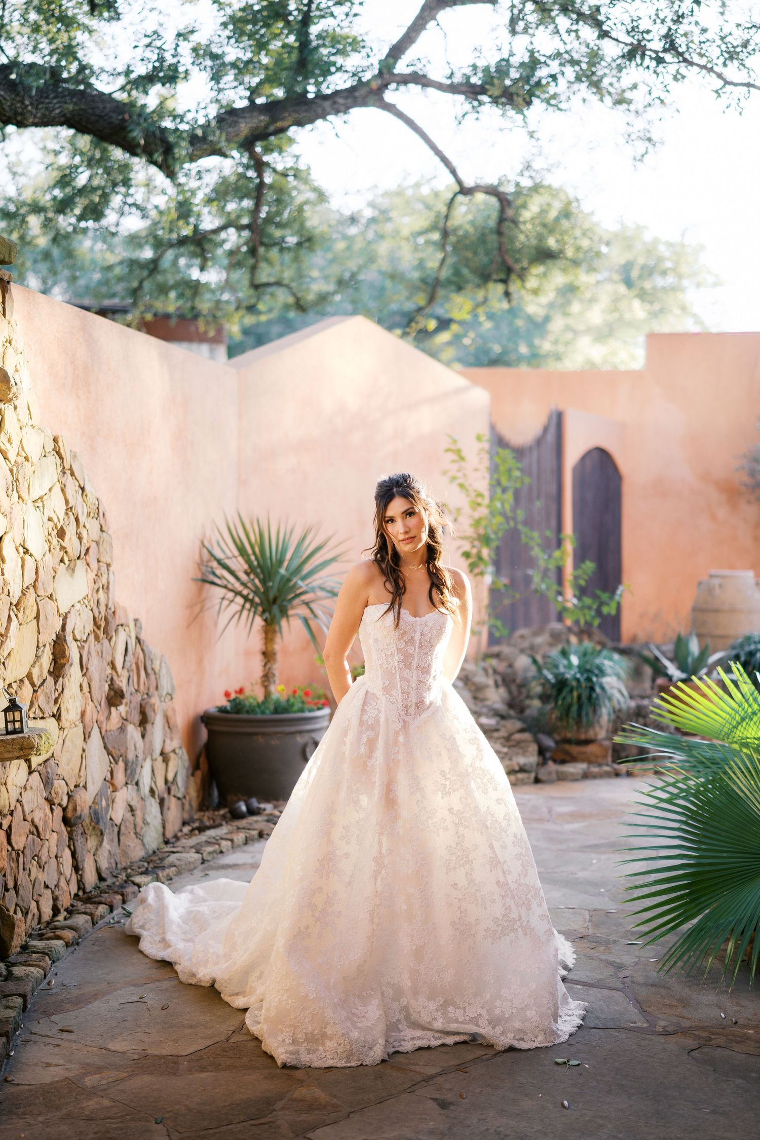 Elegant bridal portraits in a Spanish-style courtyard with terra cotta walls and lush greenery.
