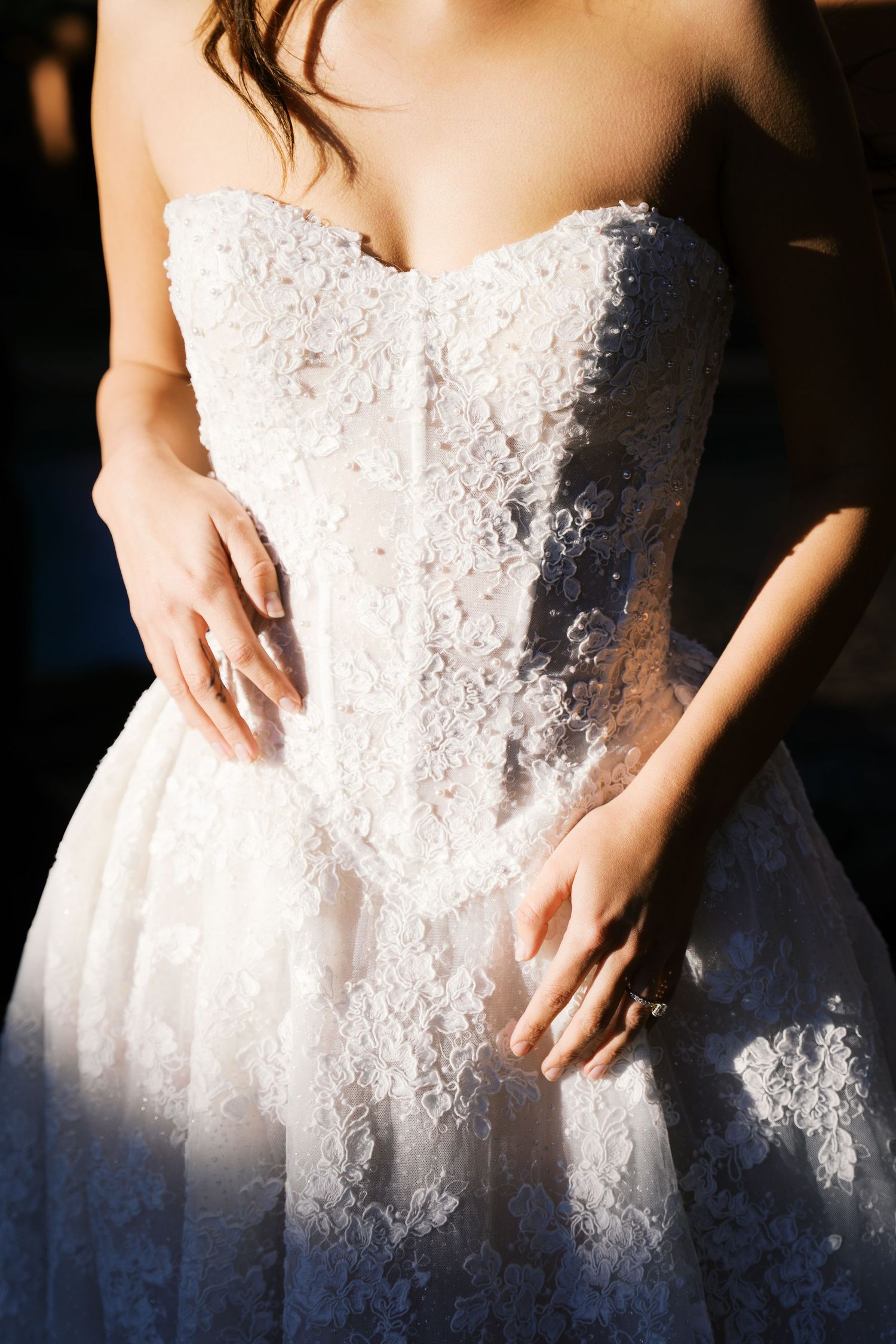 Close-up details of a white lace wedding dress bodice in natural light.