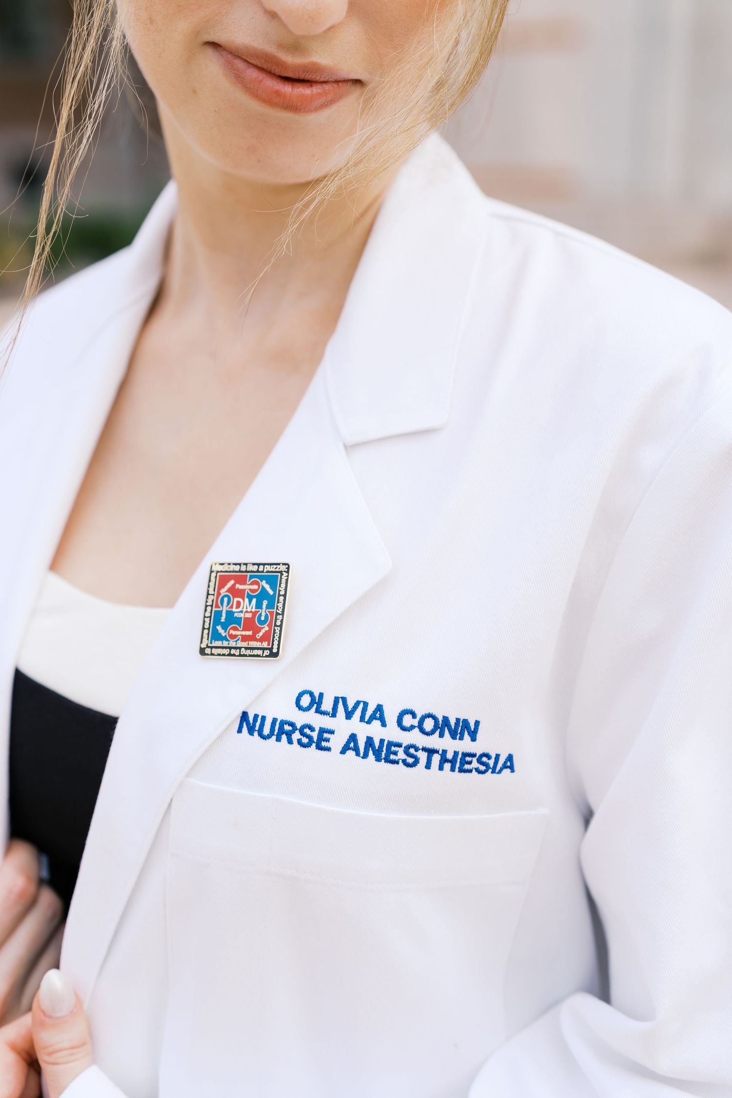 Close-up details of a white medical professional coat with name tags and credentials.