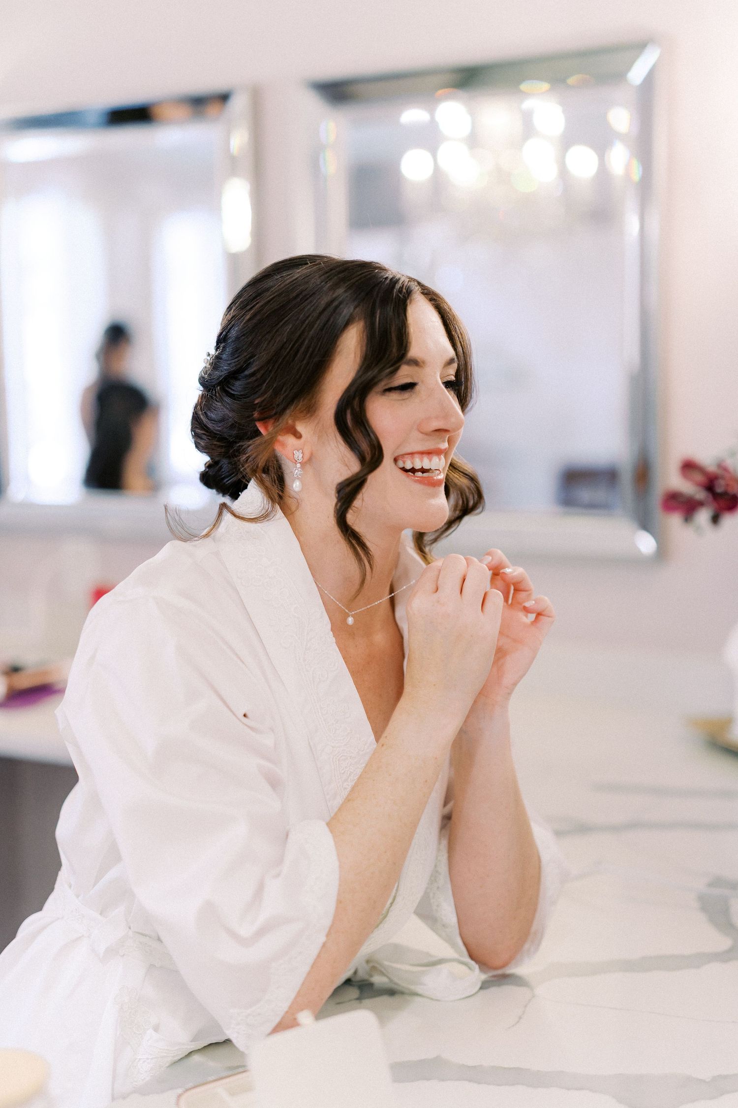 A woman in a white shirt laughs joyfully while lying down in a bright room.