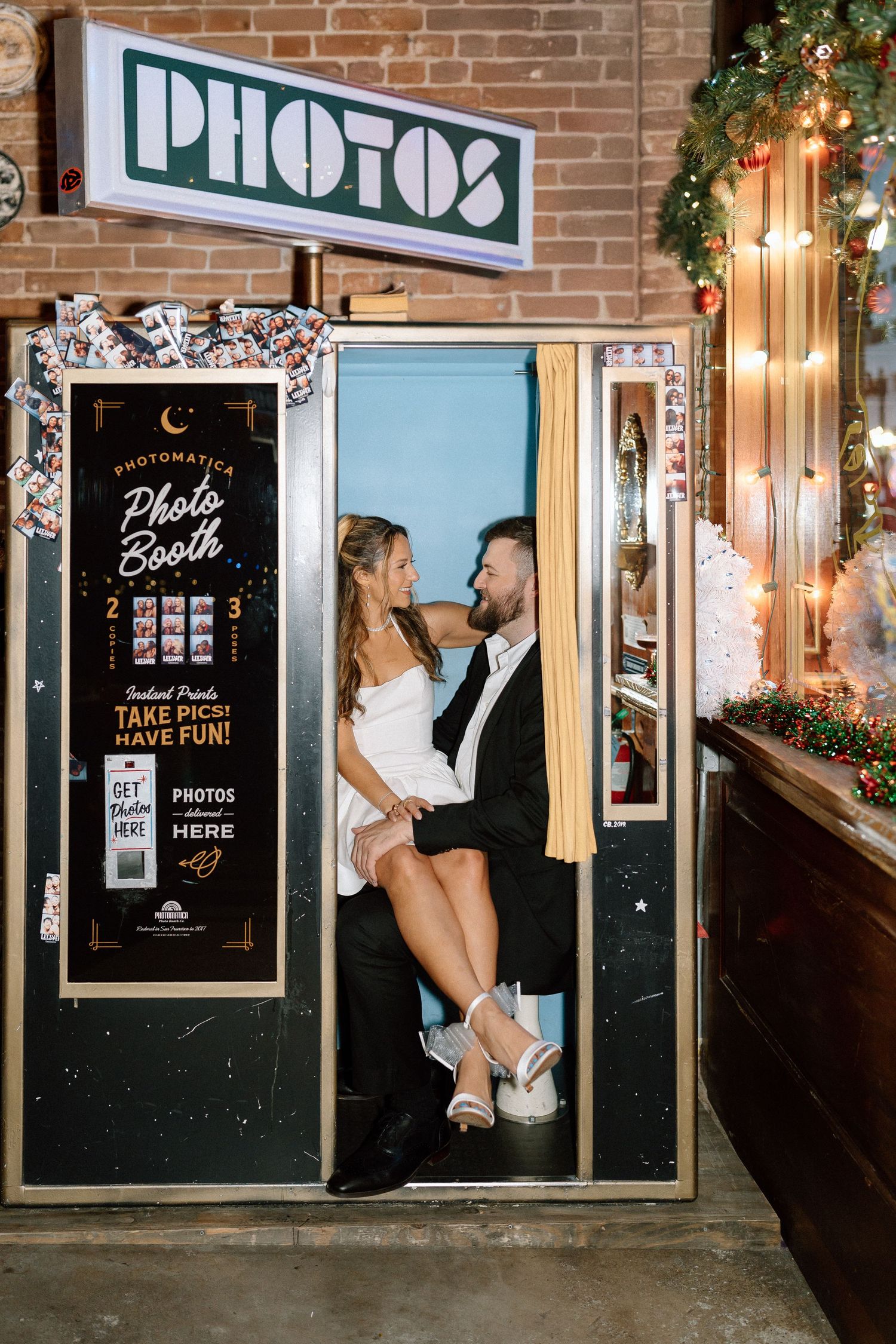 A photo booth area with vintage-style signage and decorative lighting against a brick wall.