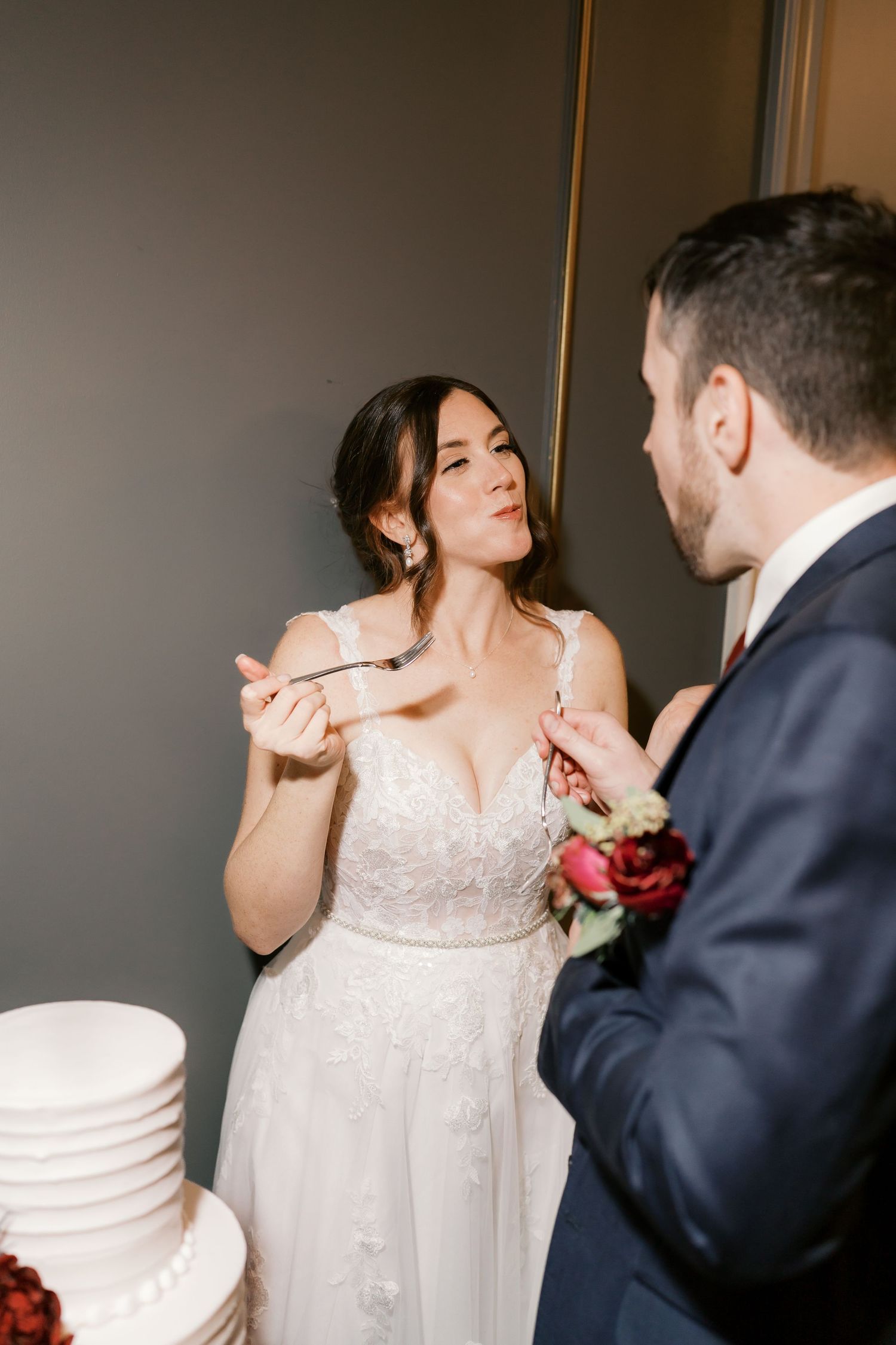 A couple in wedding attire shares an intimate moment during their cake cutting ceremony.