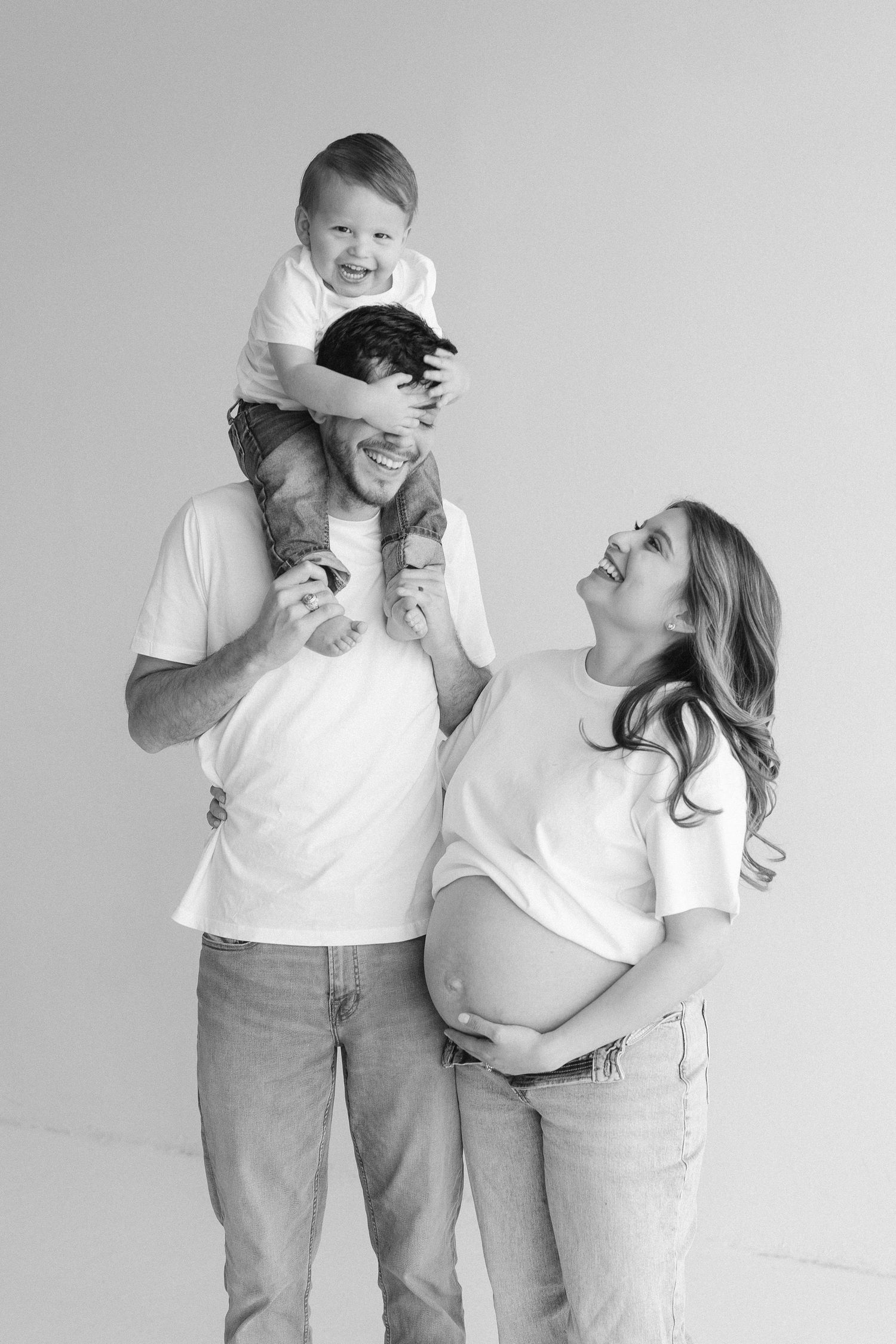 Candid black and white family photos showing laughter and joy during maternity session.