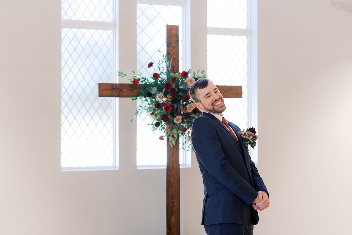 A romantic first look scene unfolds in a minimalist white church with arched windows.