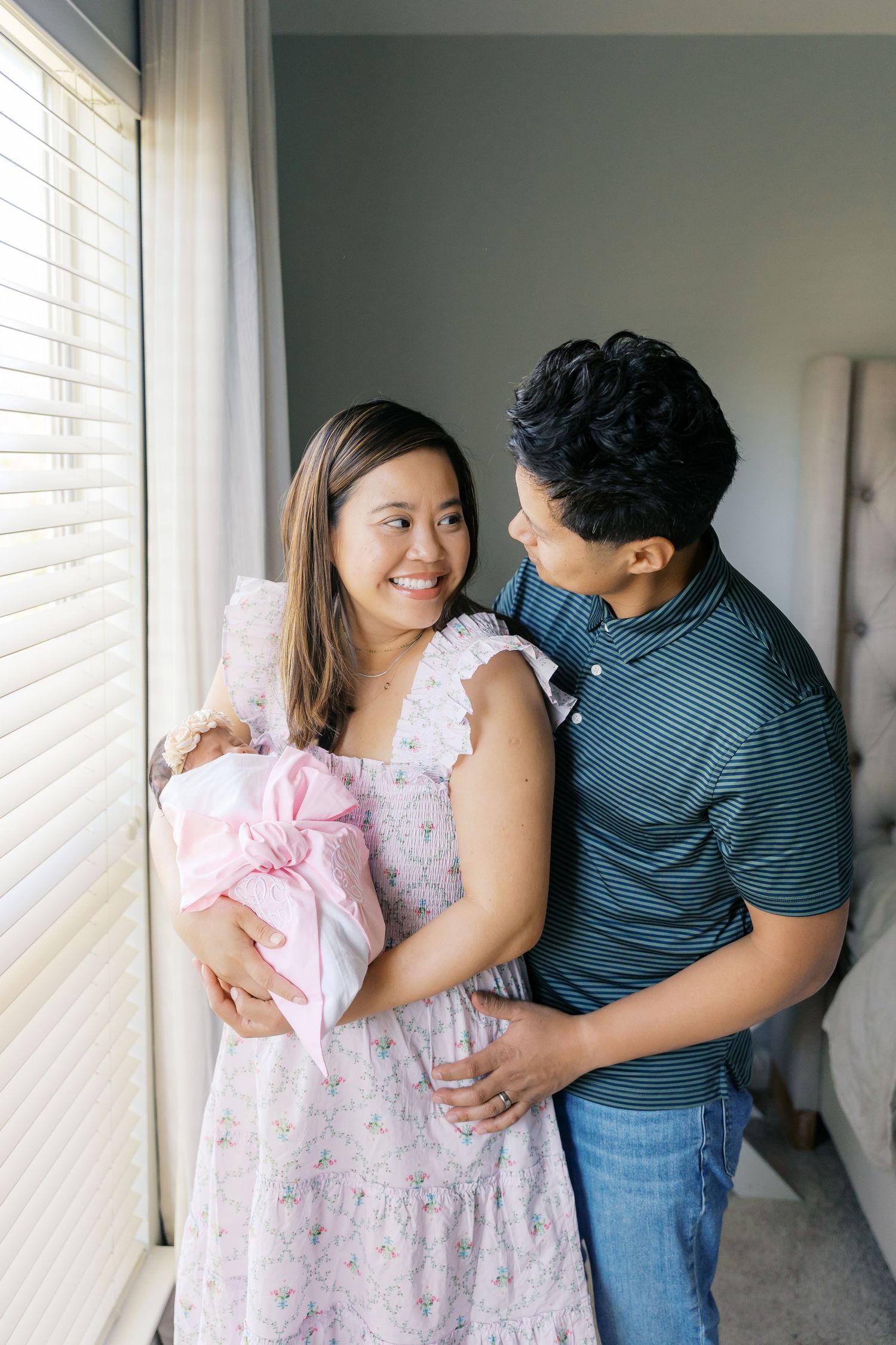 Candid lifestyle photos of a family embracing near a window with natural light.