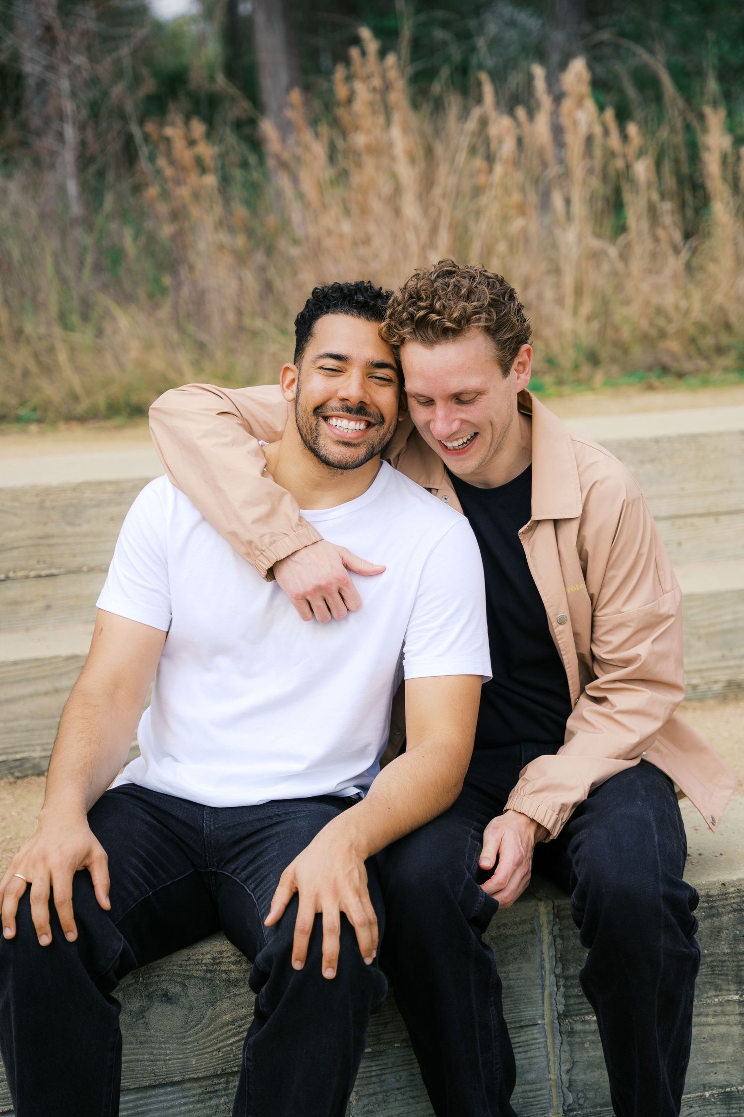 Two people sharing intimate laughs while sitting together outdoors.