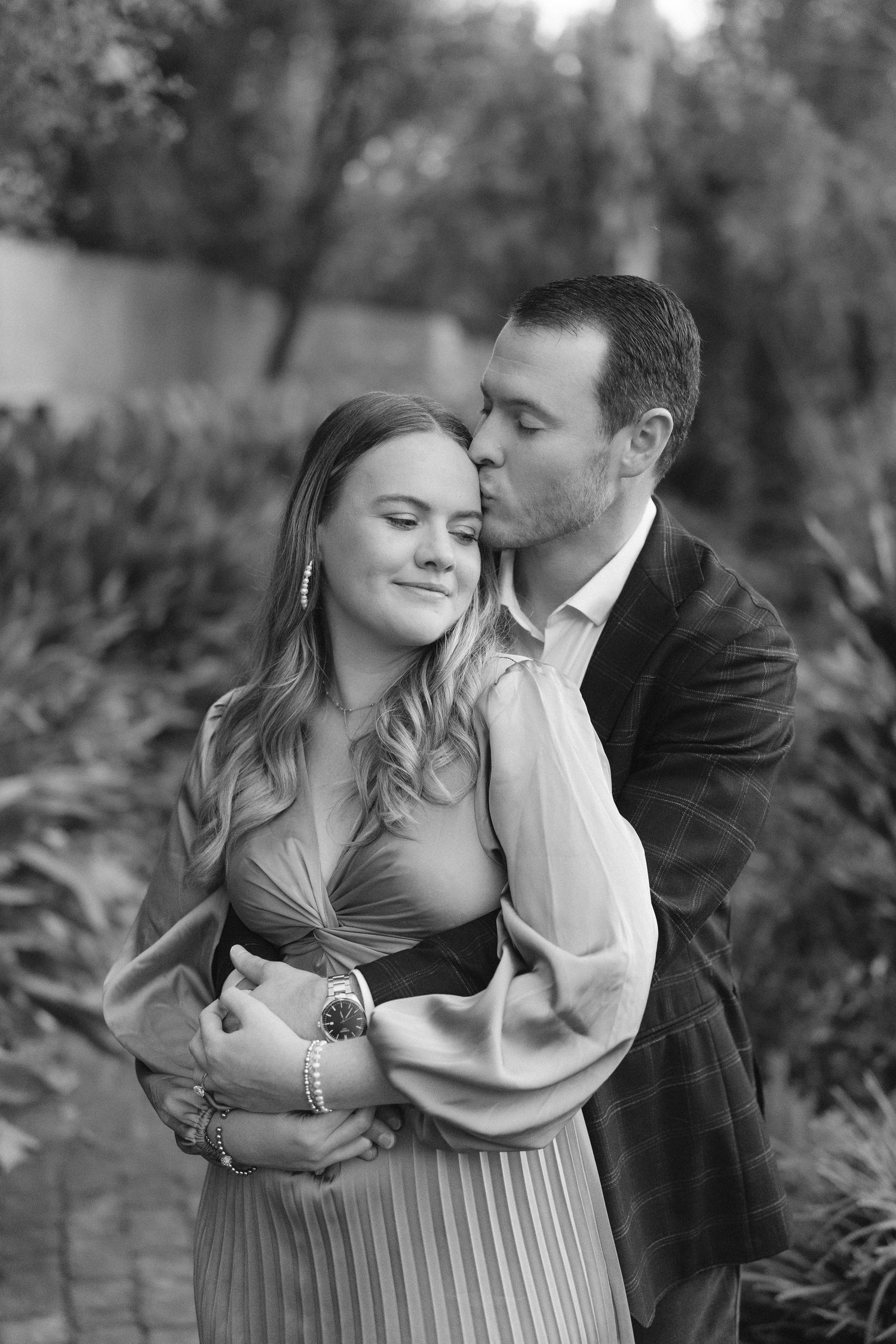 Black and white engagement photos showing tender moments between a couple in an outdoor setting.