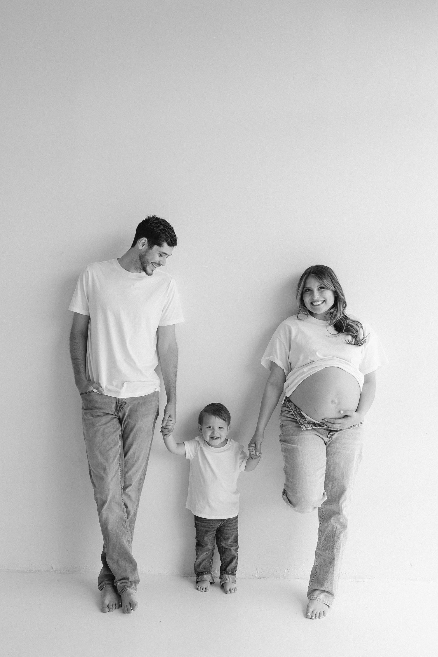 Black and white family photos showing playful poses against clean white studio backdrop.