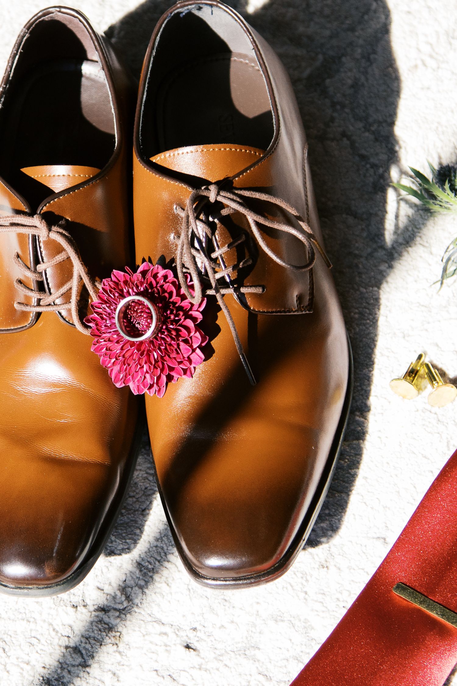 Brown leather dress shoes decorated with burgundy floral accents.