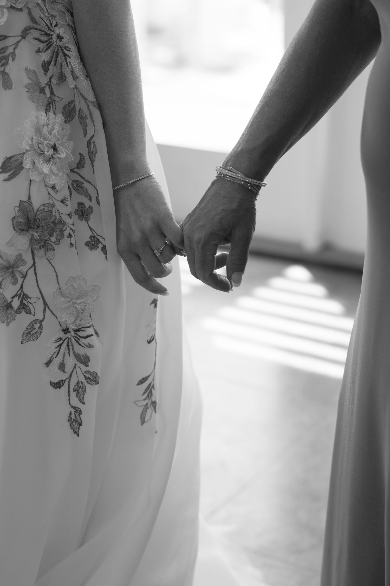 Close-up details of floral embroidered white dresses in natural window light.