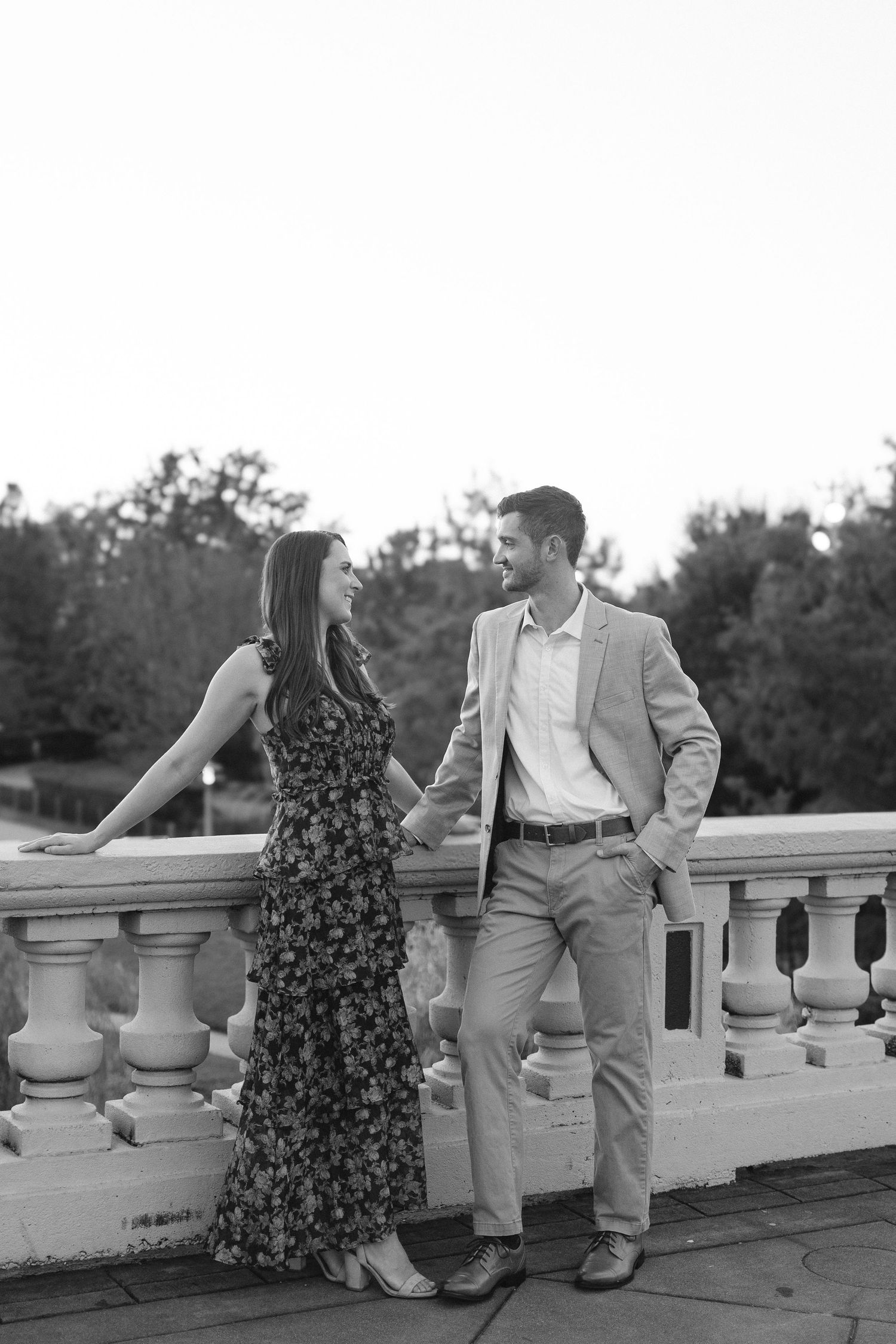 Couple posing together on a white stone balustrade in black and white.