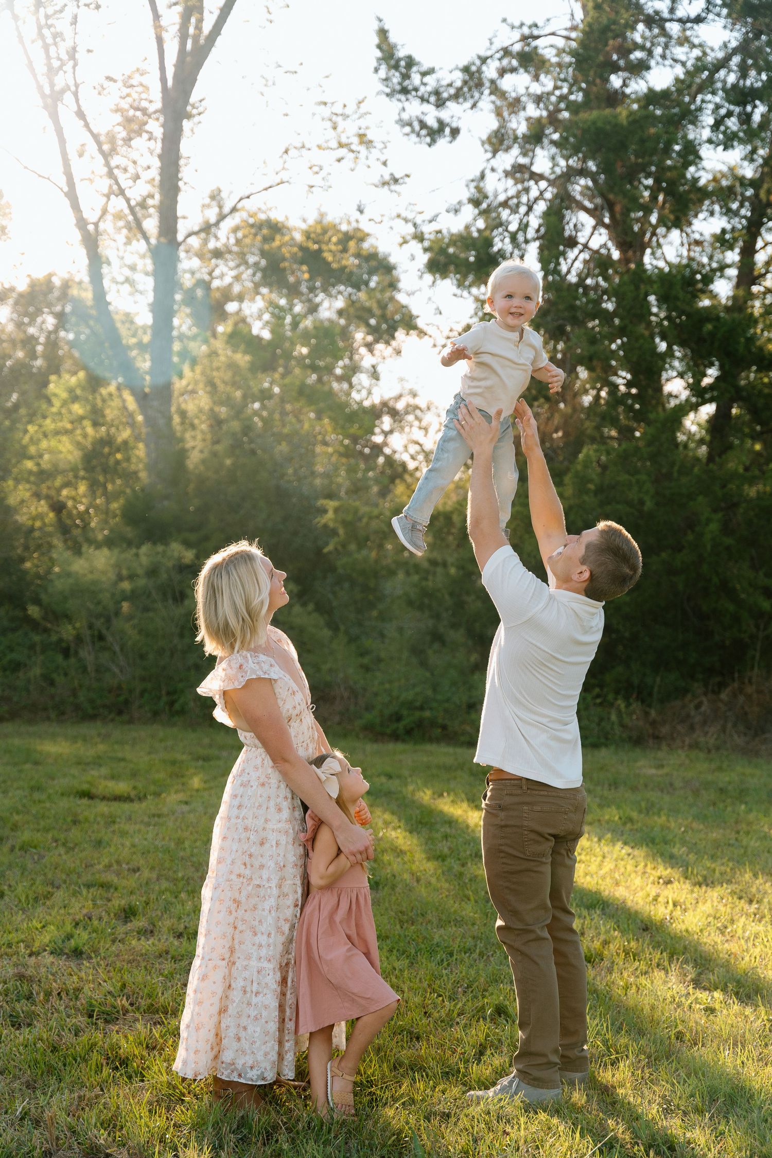Playful outdoor family moments captured at sunset in a grassy field.